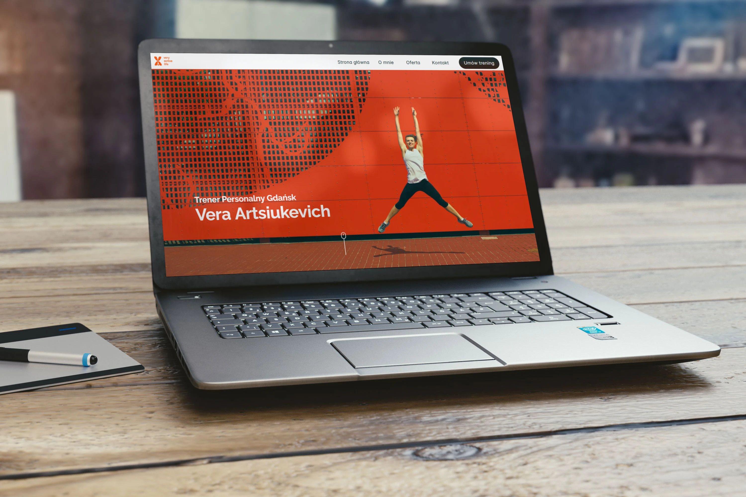 Strona VeryActiveLife wyświetalana na laptopie który stoi na drewnianym biurku