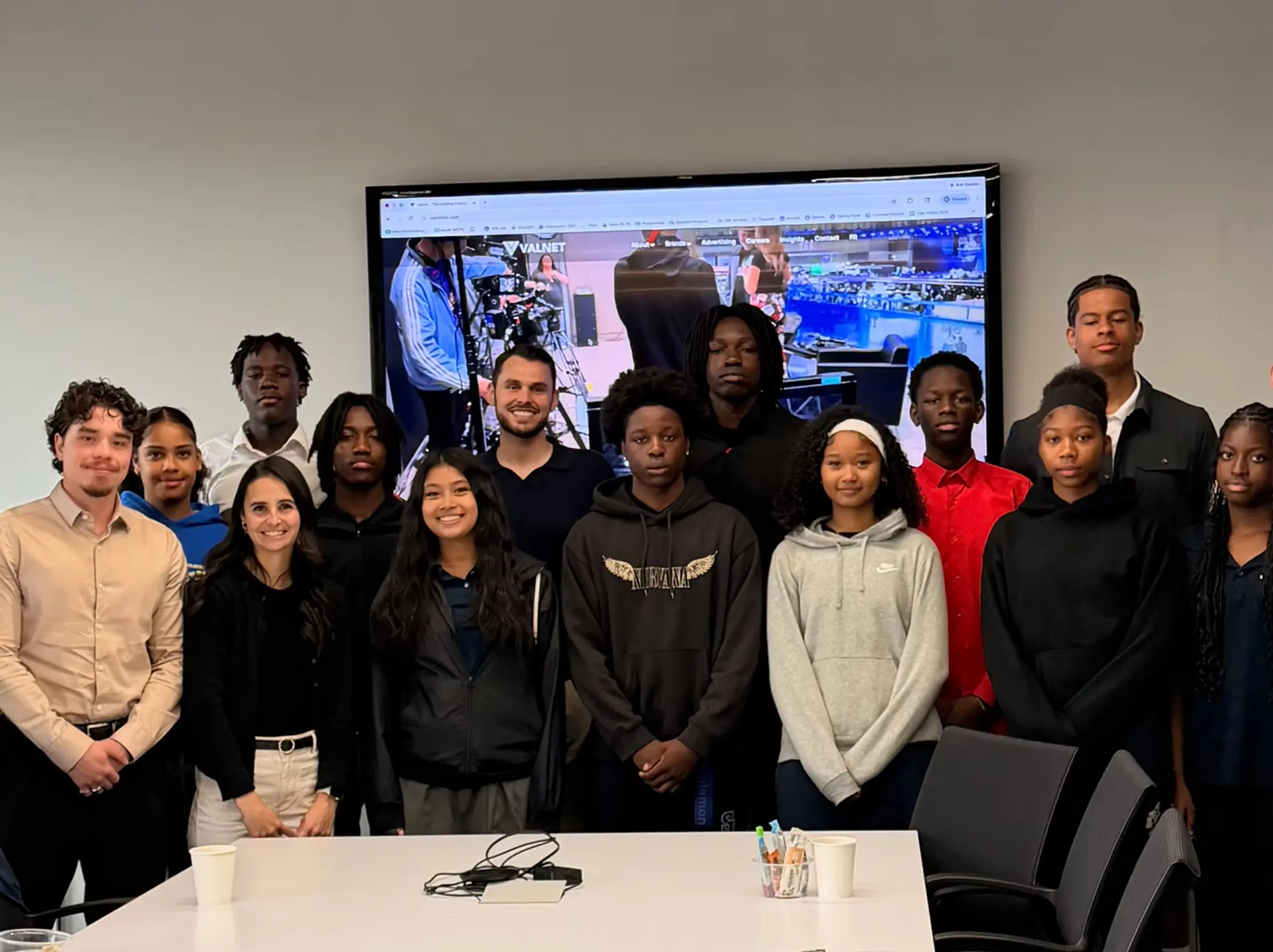 Valsoft and Valnet team members host a group of youth visitors for an office tour, with the Valnet website displayed on the screen behind them.