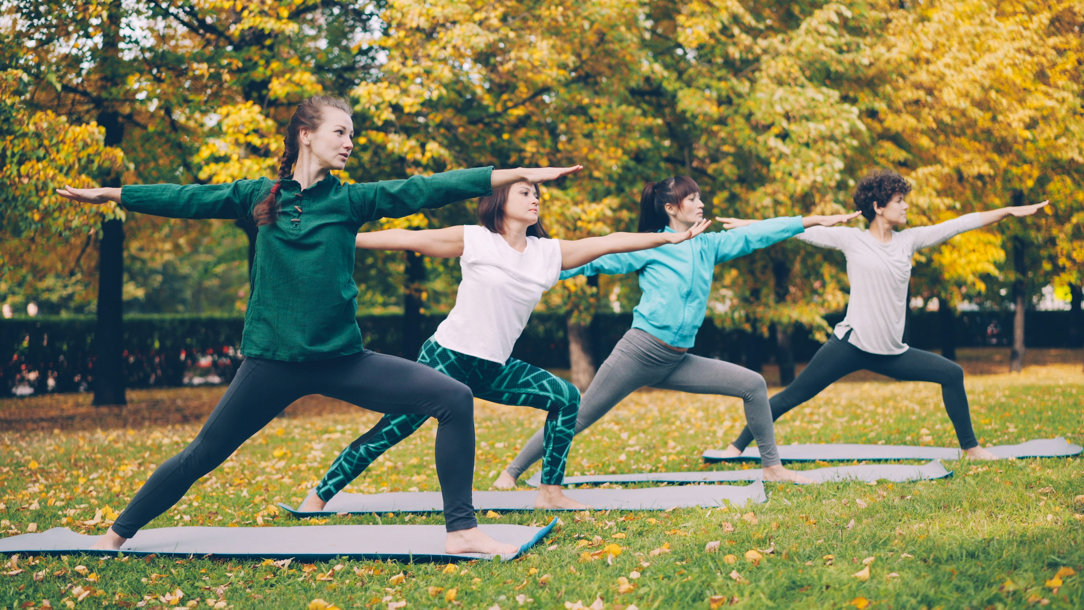 Four women practicing yoga in a park
