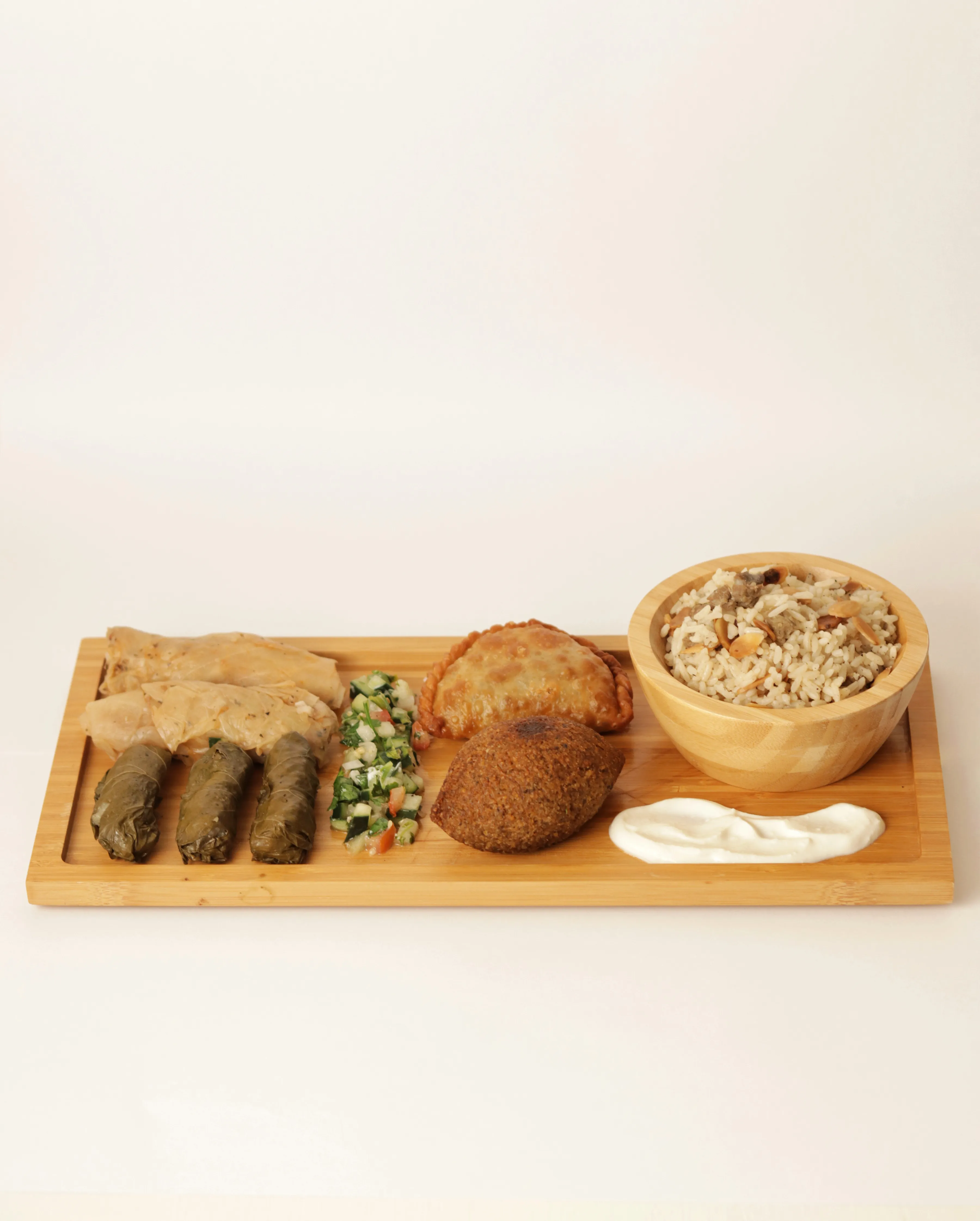 Tabla de degustación con kibbeh, arroz y hojas de parra.