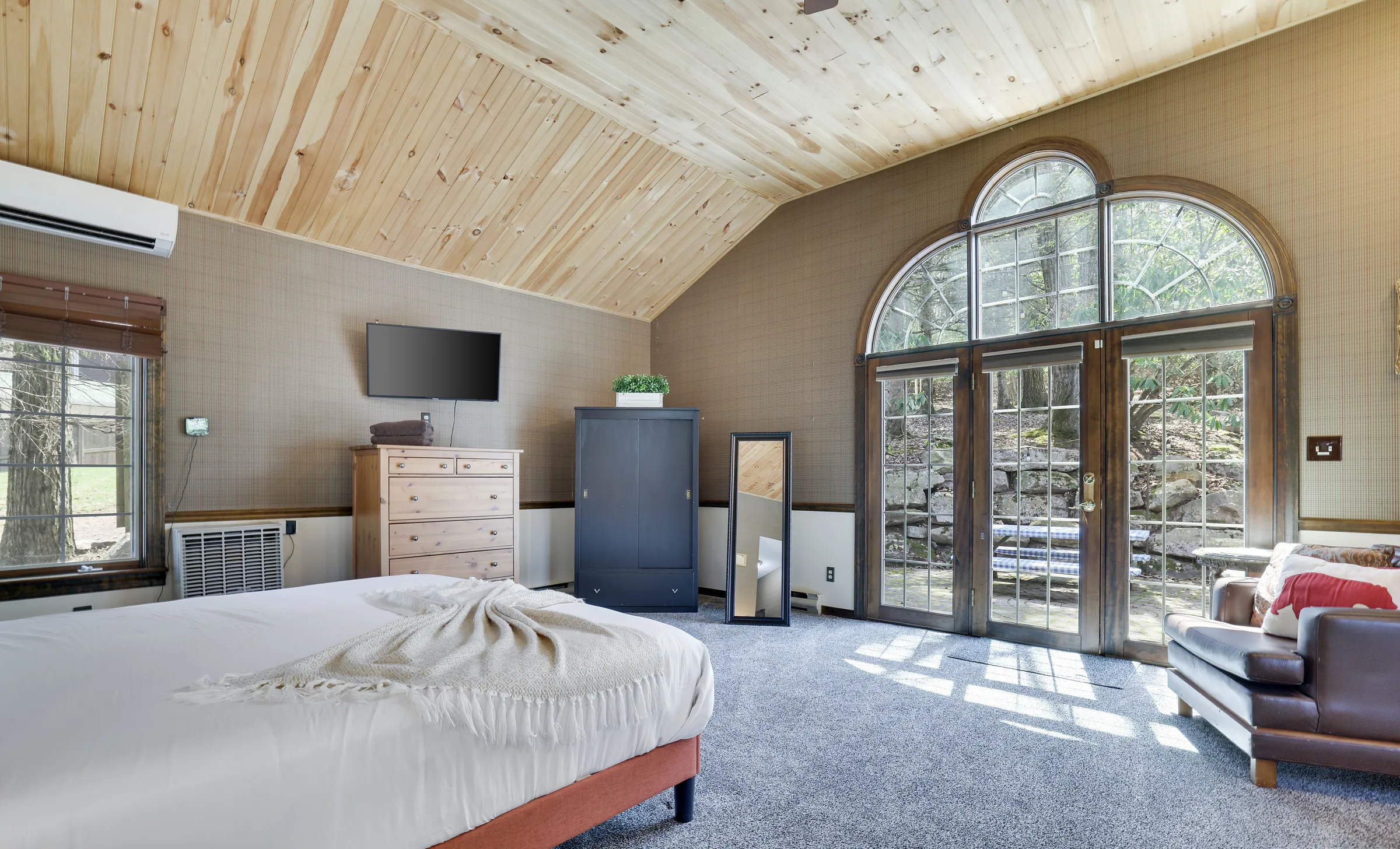 King bedroom with vaulted pine ceiling, arched doors and seating at Repeat Retreat
