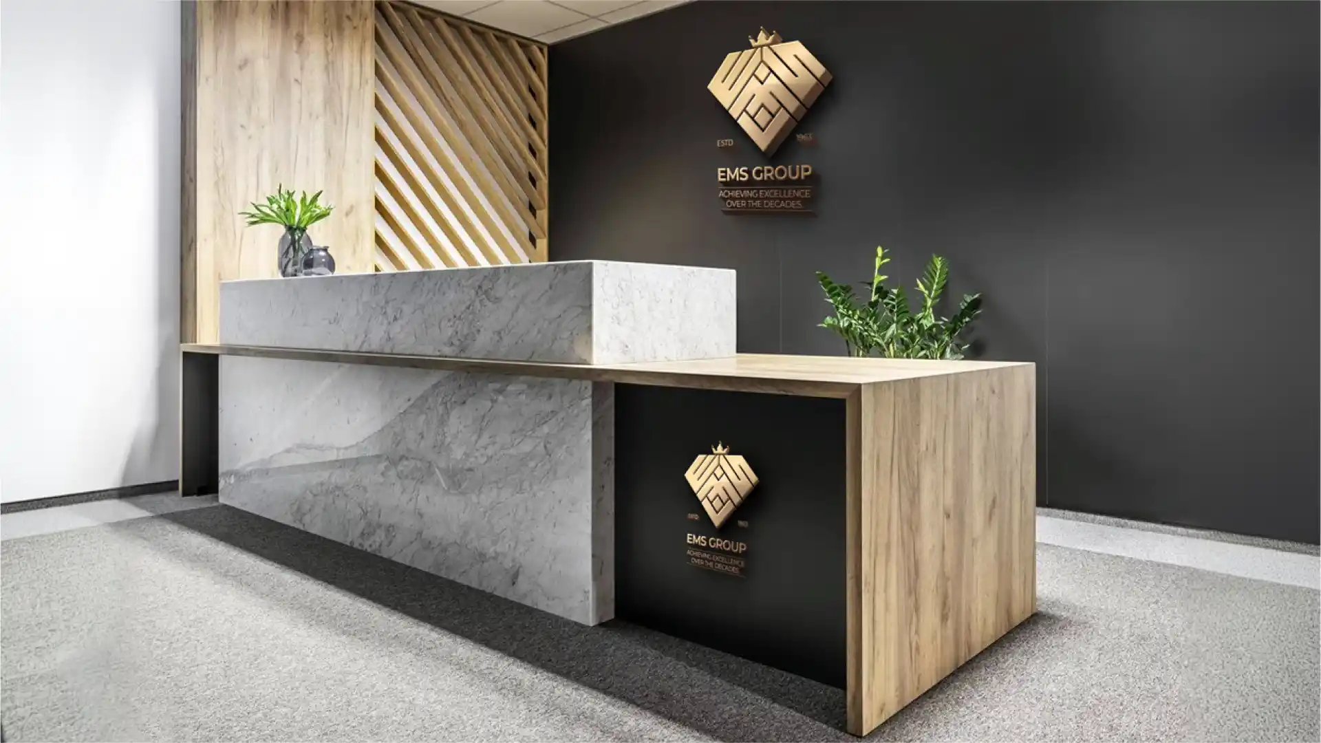 EMS Group reception desk environmental branding with gold logo signage