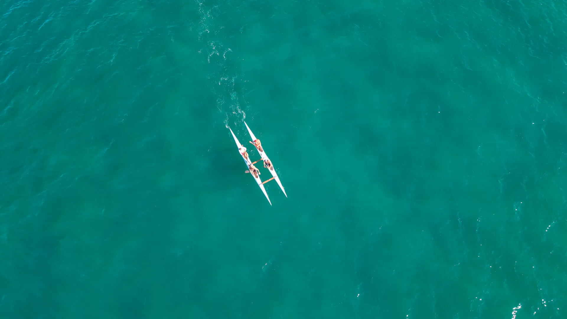 Aerial view of an outrigger canoe paddling over turquoise water off Malpaís, Costa Rica