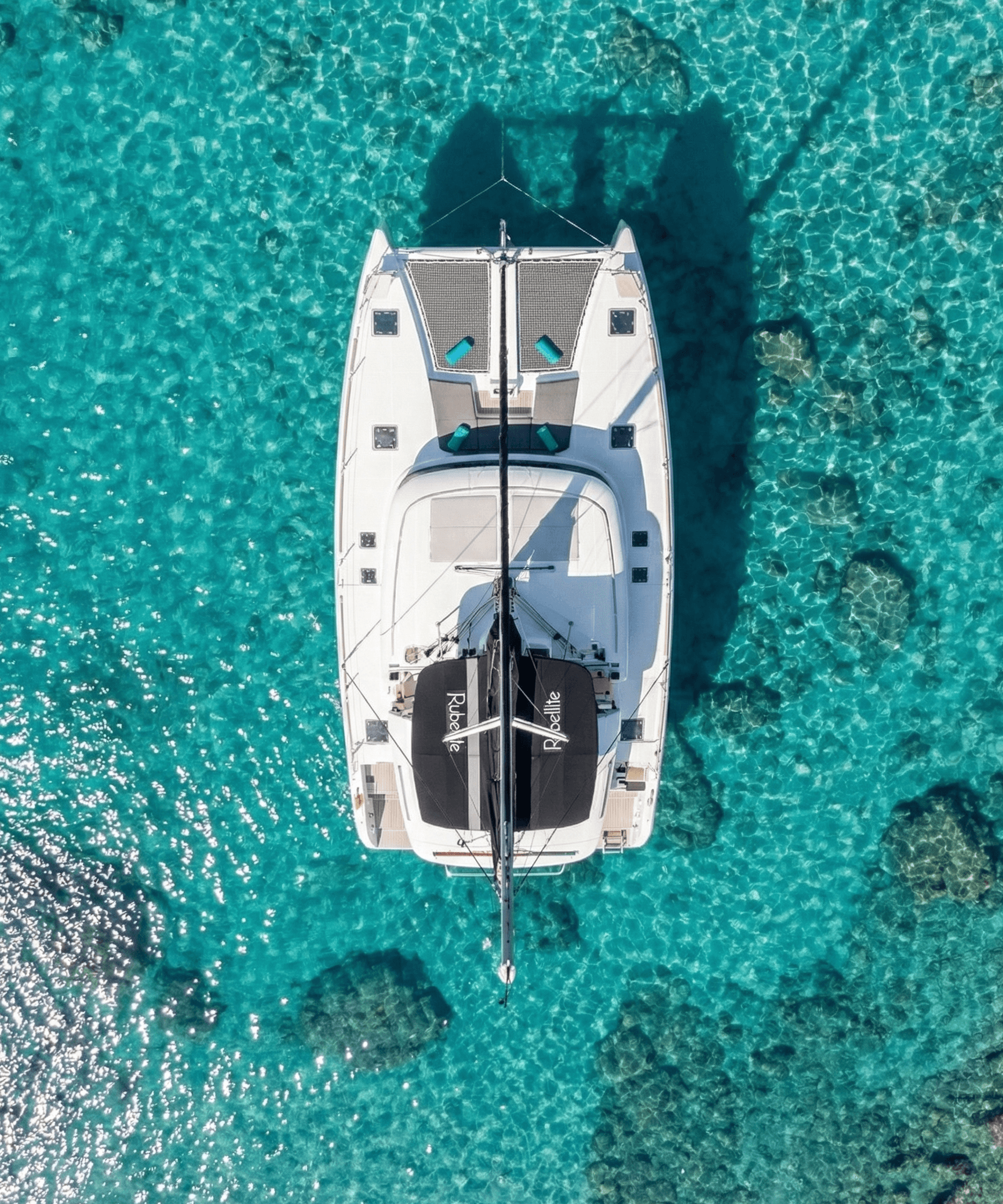 Aerial view of white Rock 36 motor yacht anchored in crystal-clear turquoise waters of the Aegean Sea