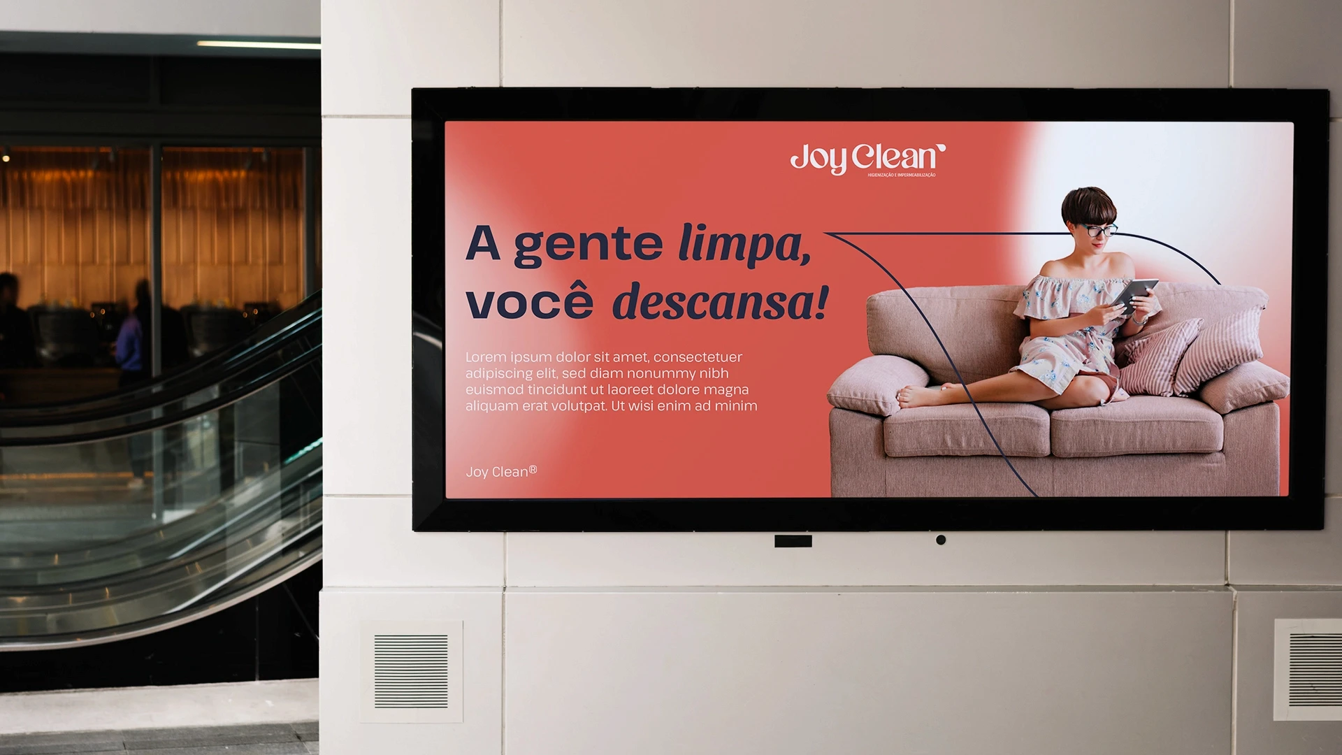 Painel publicitário digital instalado em ambiente interno com o slogan 'A gente limpa, você descansa!' ao lado de uma foto de uma mulher relaxando em um sofá limpo com tablet.