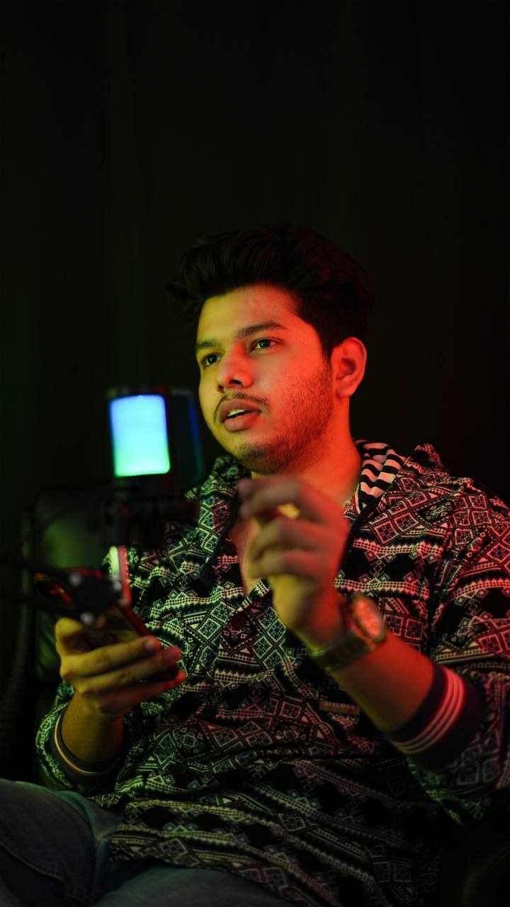 Close-up portrait of a person wearing a gray insulated hooded jacket with the hood up, showing their face framed by the hood against a light background.