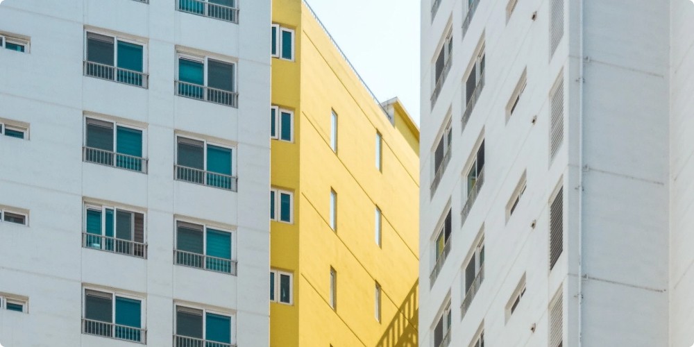 two grey tower blocks with a yellow towerblock between them