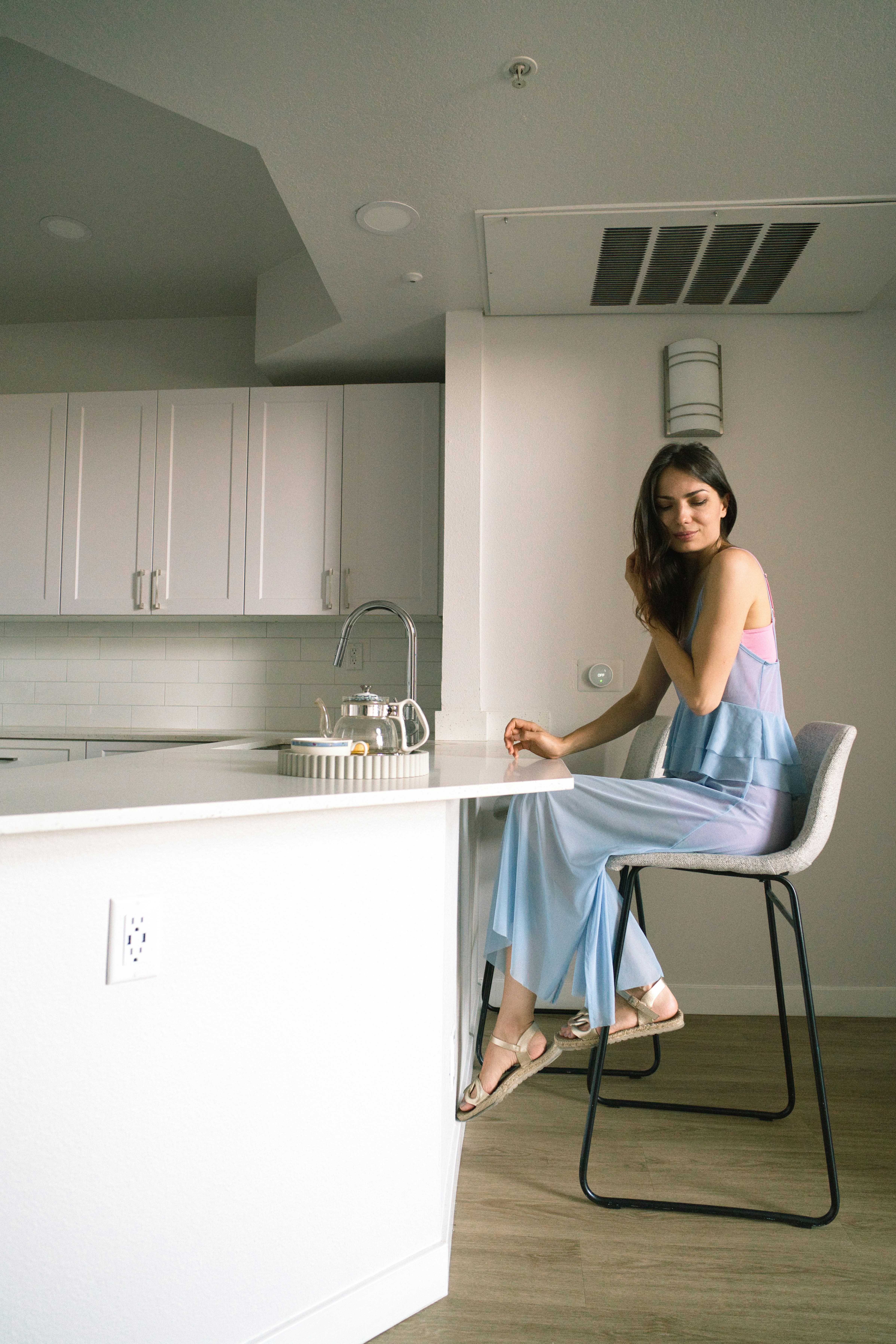 A woman sits at a kitchen counter.