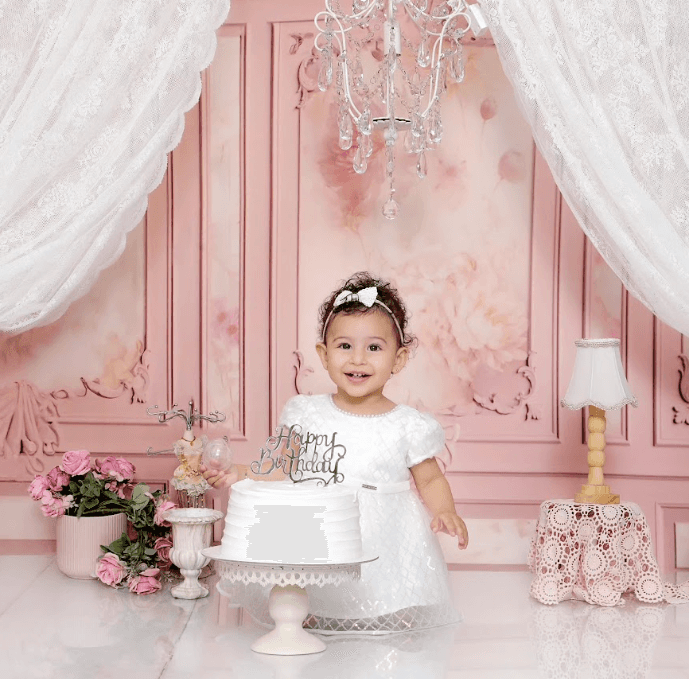Baby smiling for the camera, surrounded by pink flowers and curtains.