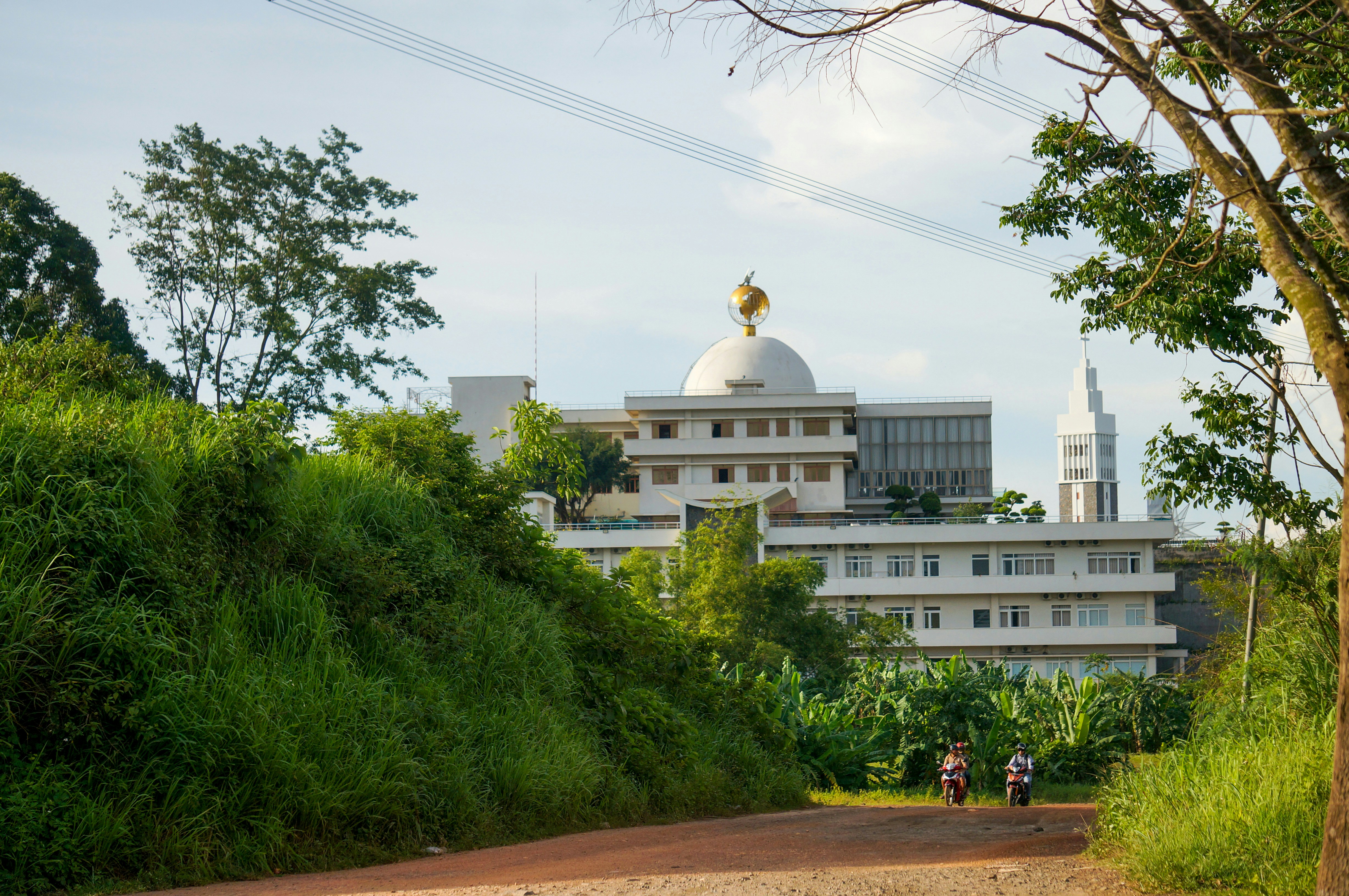 Modern white building with golden dome and spire.