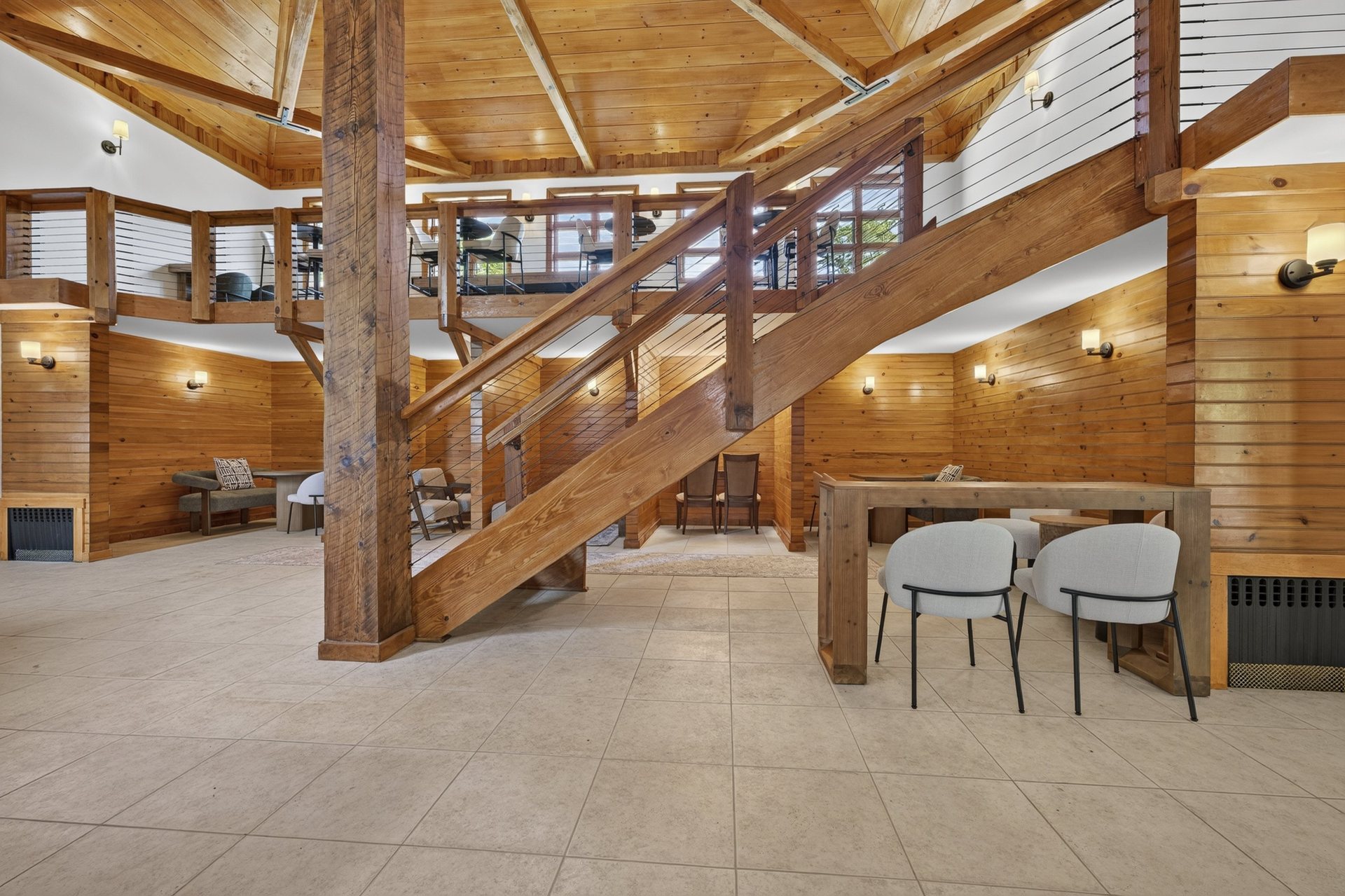 The atrium with its timber staircase, lounge chairs and a long table