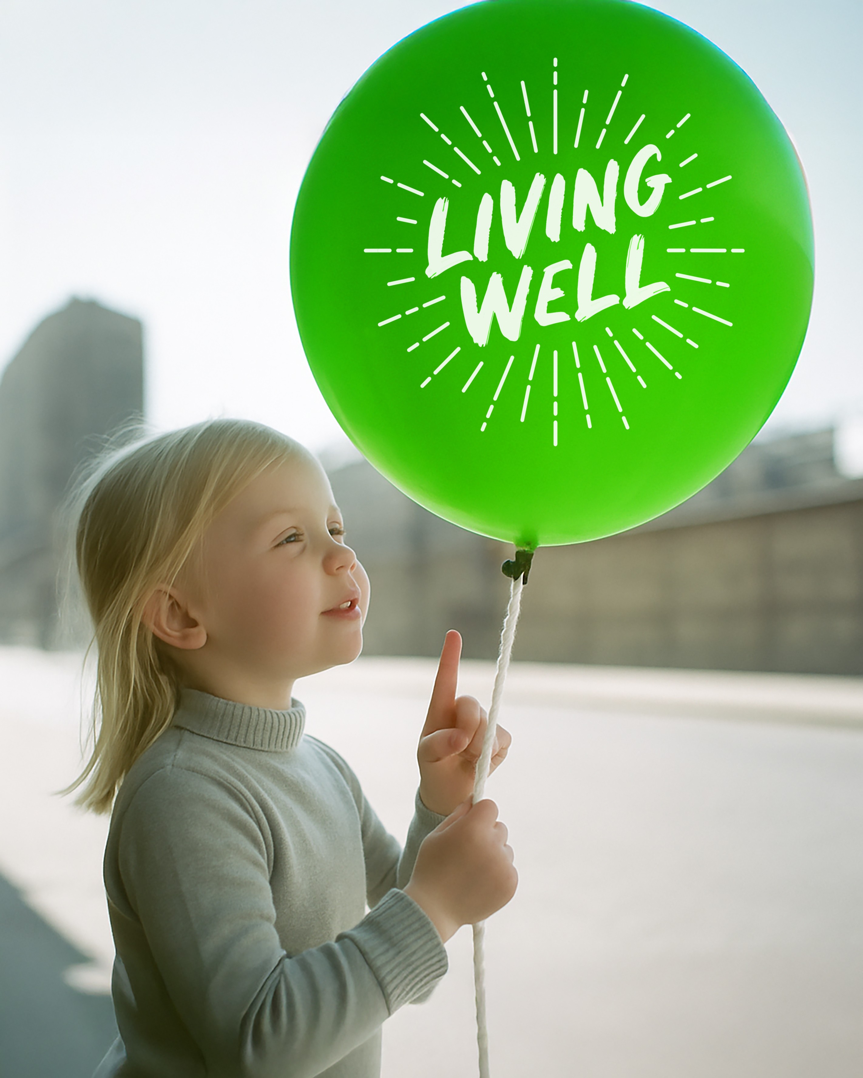 Girl with green balloon with Living Well logo on