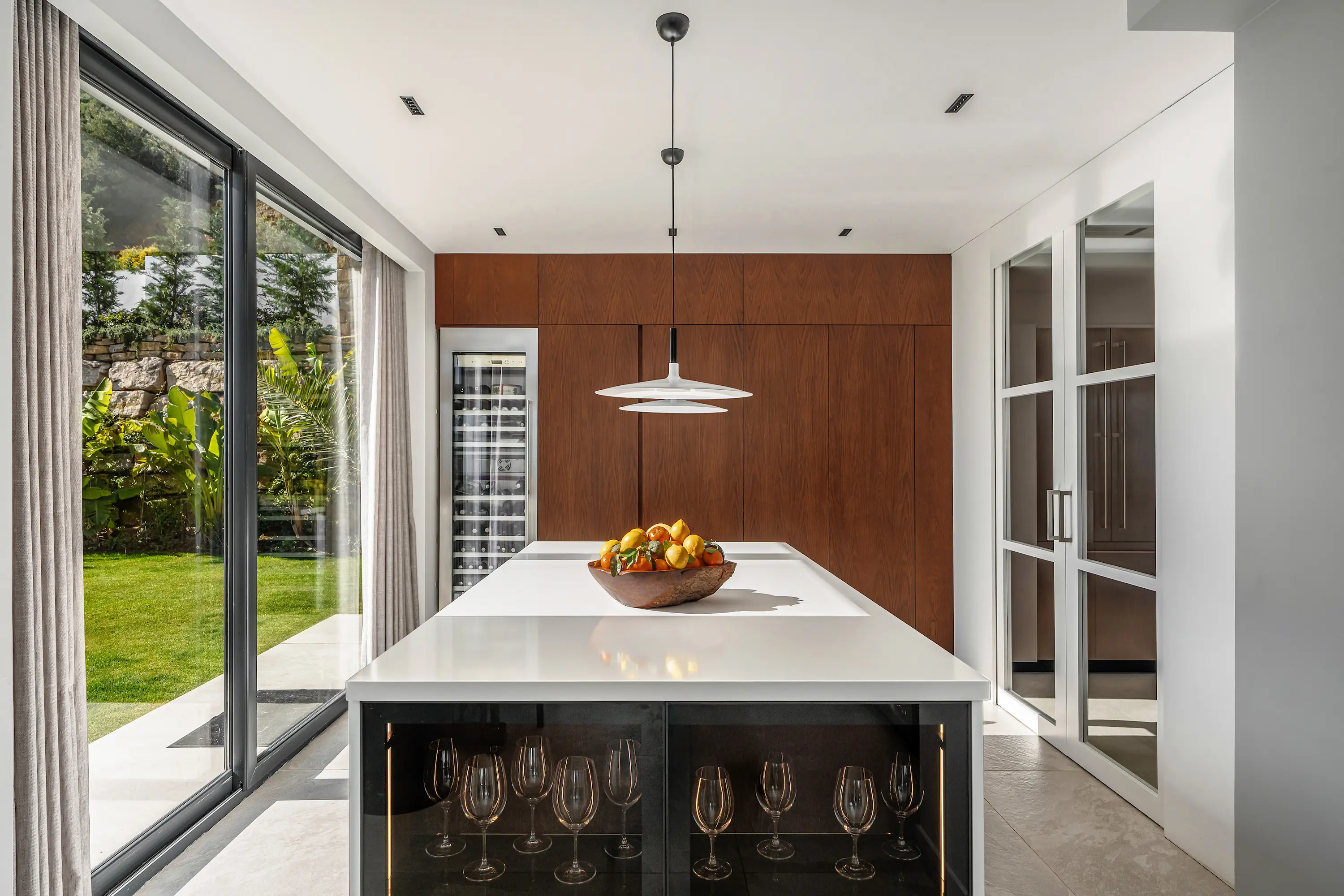 Villa Vista Marbella kitchen with white waterfall island, pendant lighting, and warm wood cabinetry