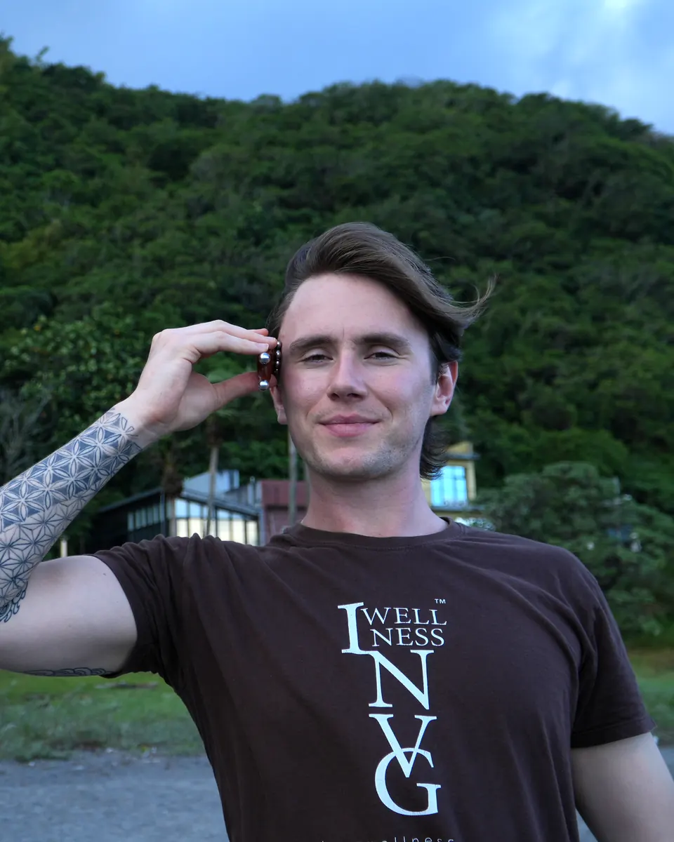 Jude Massey in an INVG Wellness T-shirt pressing a point by his temple with a small tool