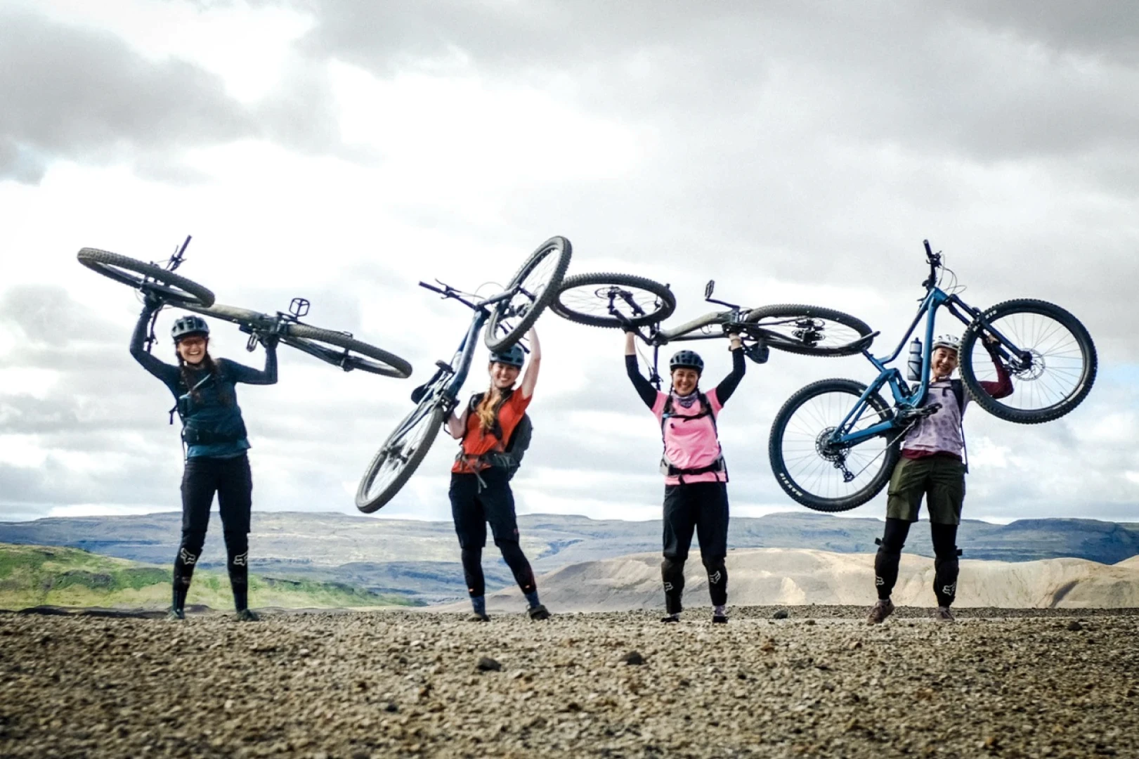 Four women hold their bikes over their heads for a picture on Icebike trip