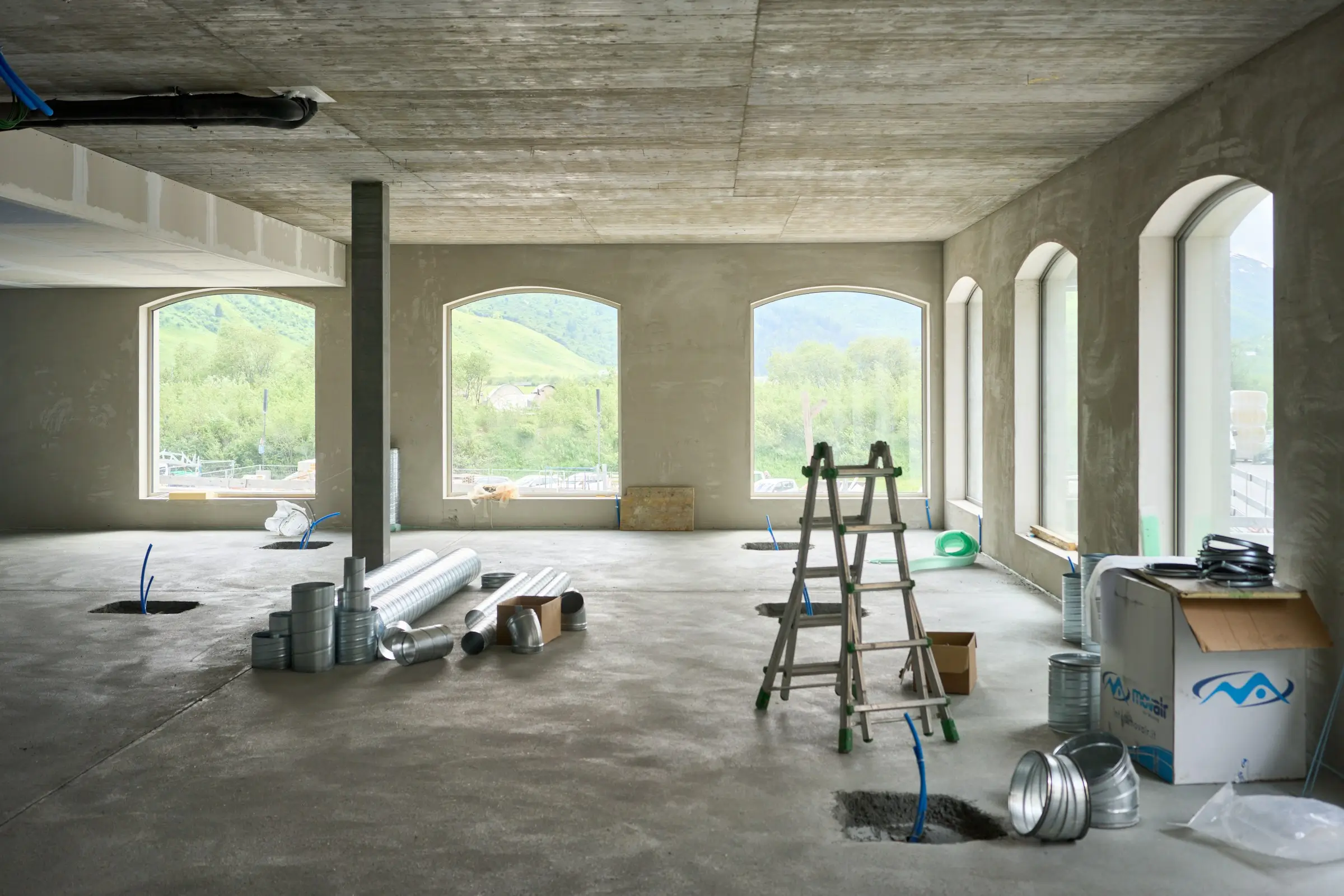 A vacant room featuring a ladder and various tools scattered around, suggesting a space for work or renovation.