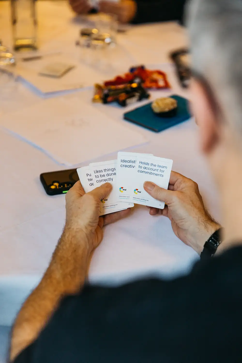 Person pointing a object at an electronic device on the table.