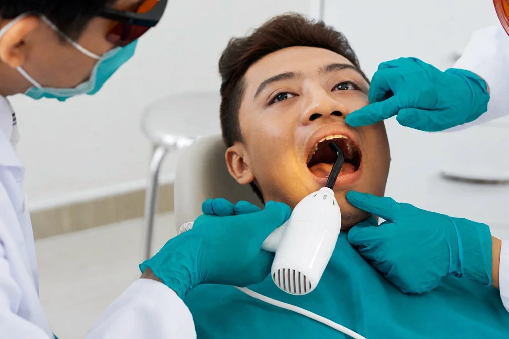 Patient opening wide during a dental checkup while the practitioner inspects the oral cavity.