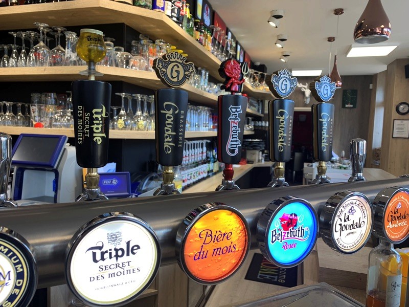 Modern living room with abstract art, beige sectional sofa, indoor plants, and large windows.