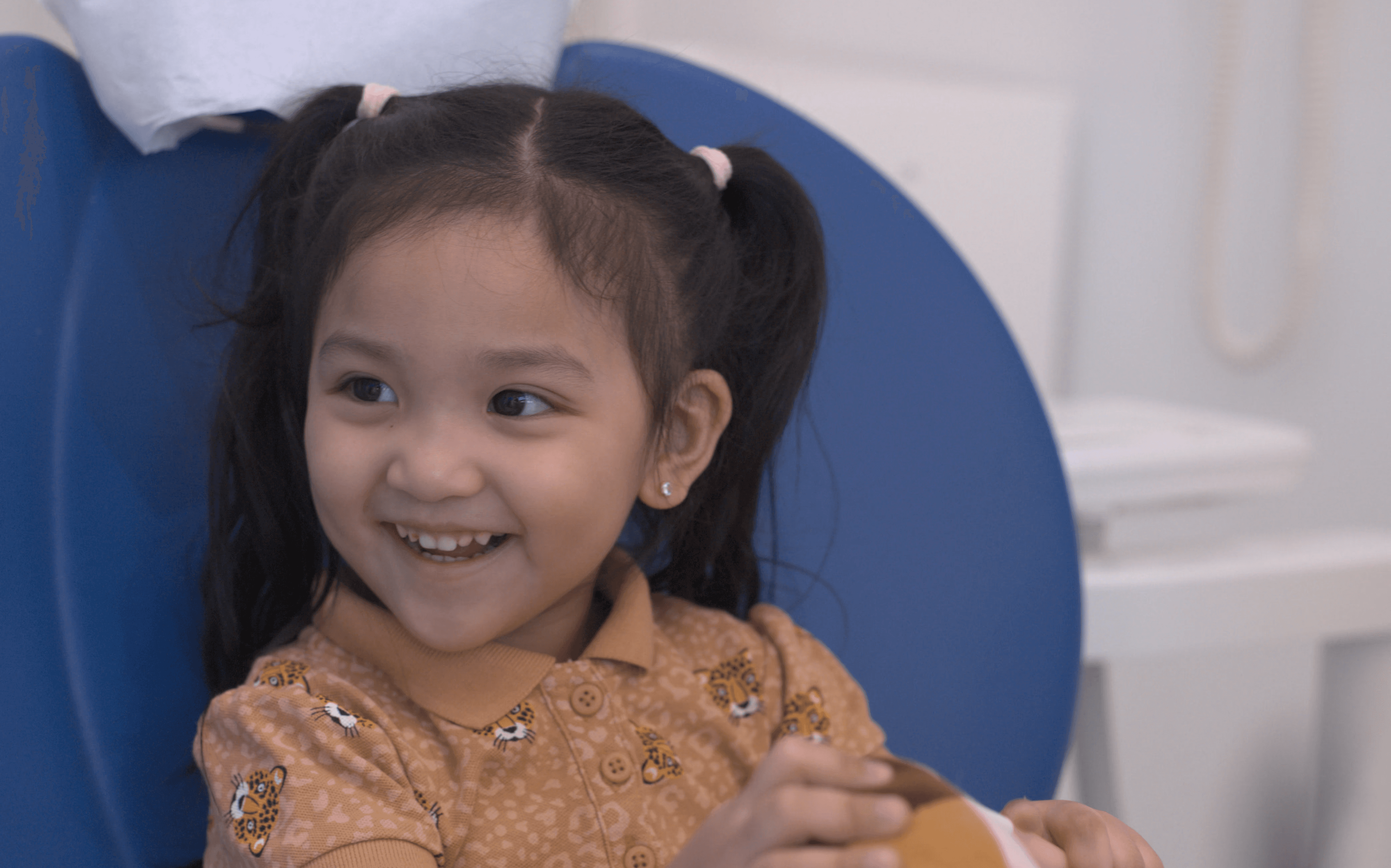 A little kid with a big smile after having her teeth checked by an Invisalign dentist to avoid having tooth cavity