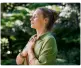 Persona con los ojos cerrados y las manos sobre el pecho, en actitud de calma y conexión, rodeada de naturaleza verde.