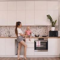 Smiling woman wearing glasses and a pink blazer on a warm pastel background.