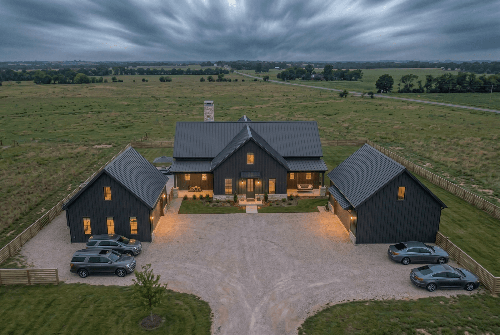 A large black house with two cars parked in front, showcasing modern residential architecture and design.