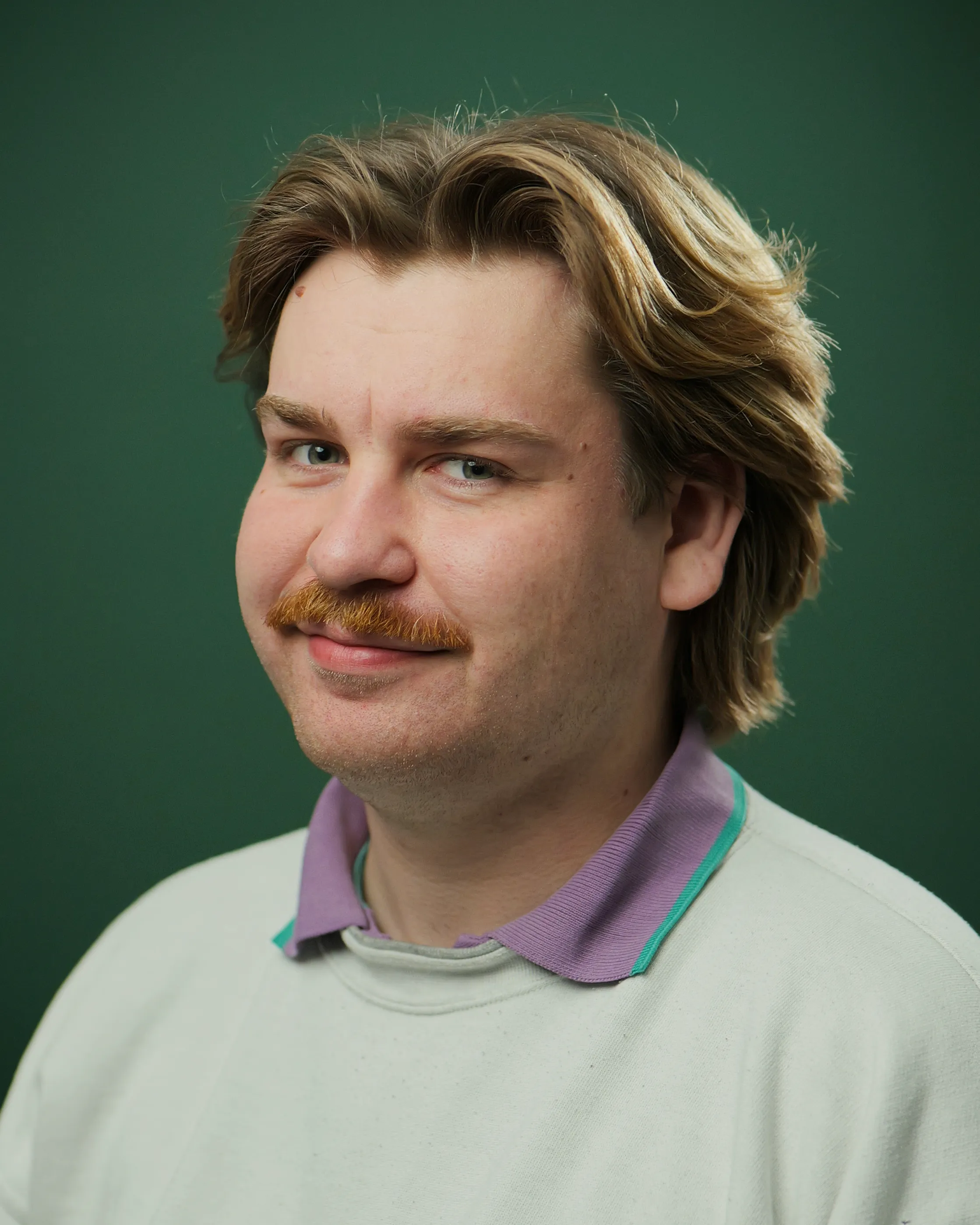 Videoproduktion Dresden Mann schaut in die Kamera. Profilbild vor grünem Hintergrund.