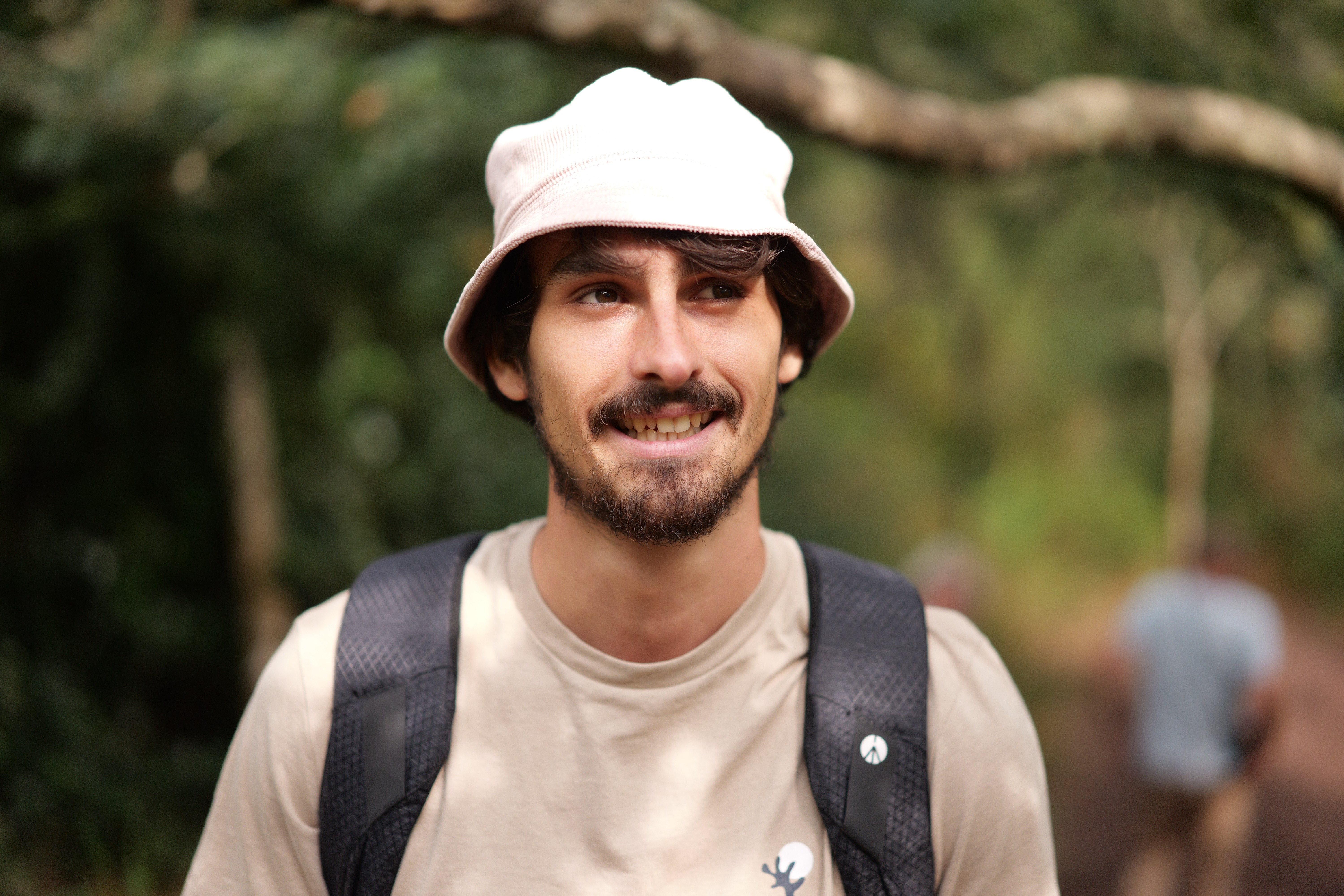 A young person in silver sports sunglasses, a white shirt, and a black sweater sits on the floor, holding an open book and leaning against a teal couch.