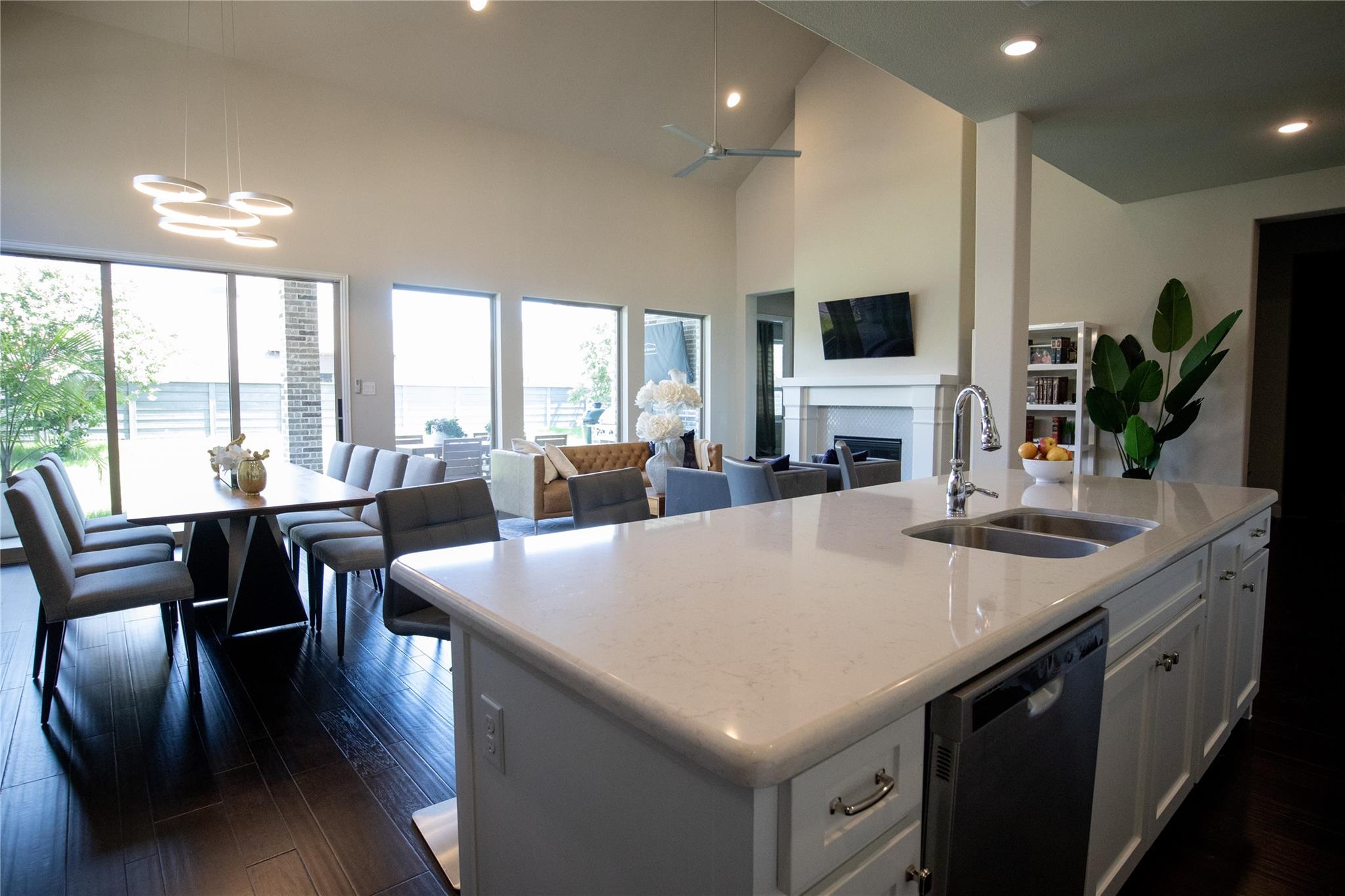 Kitchen with white cabinetry, open floor plan, a fireplace, dishwashing machine, and a center island with sink