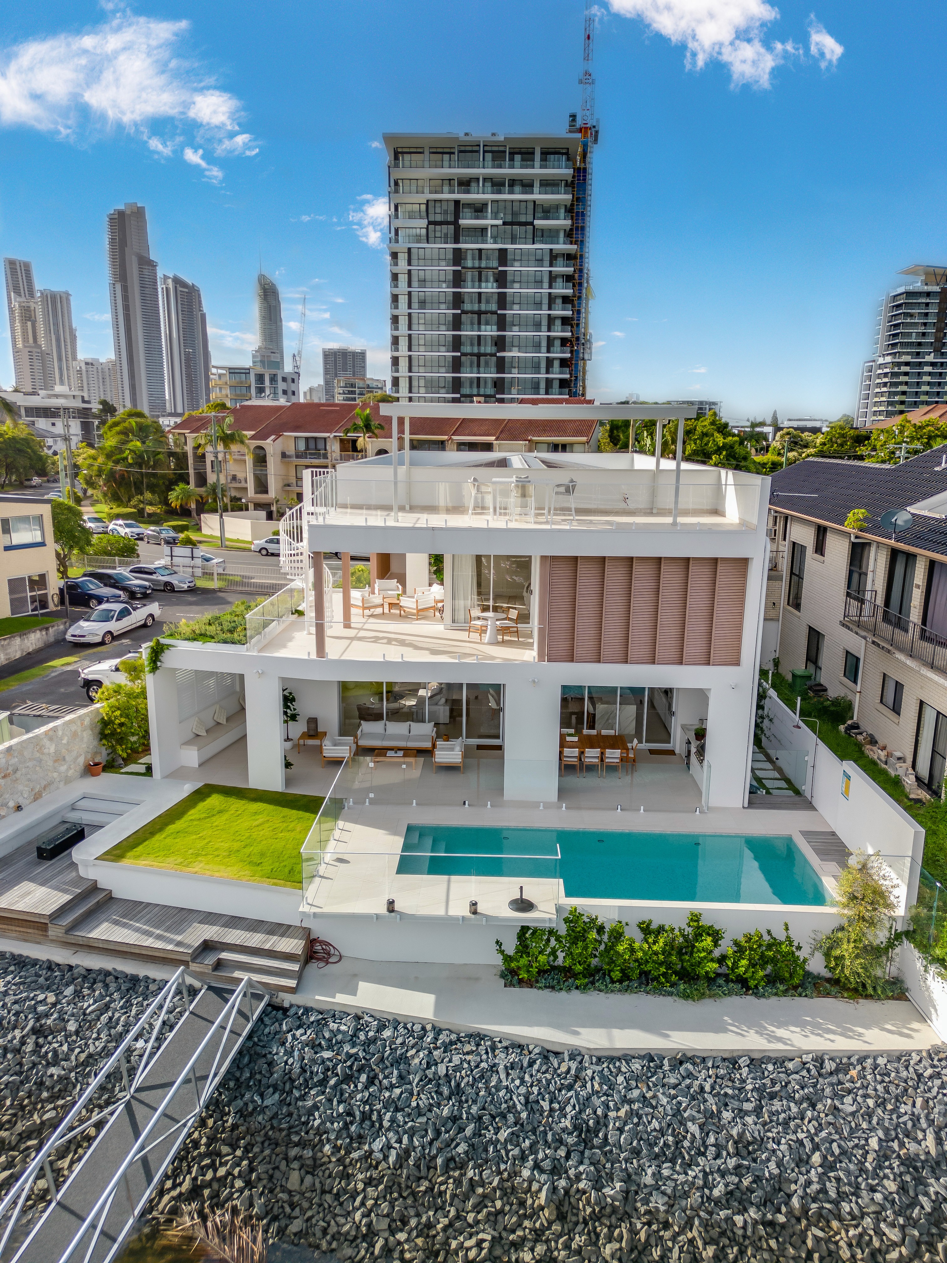 A winding road cuts through rocky terrain, surrounded by patches of green grass and illuminated by sunlight.