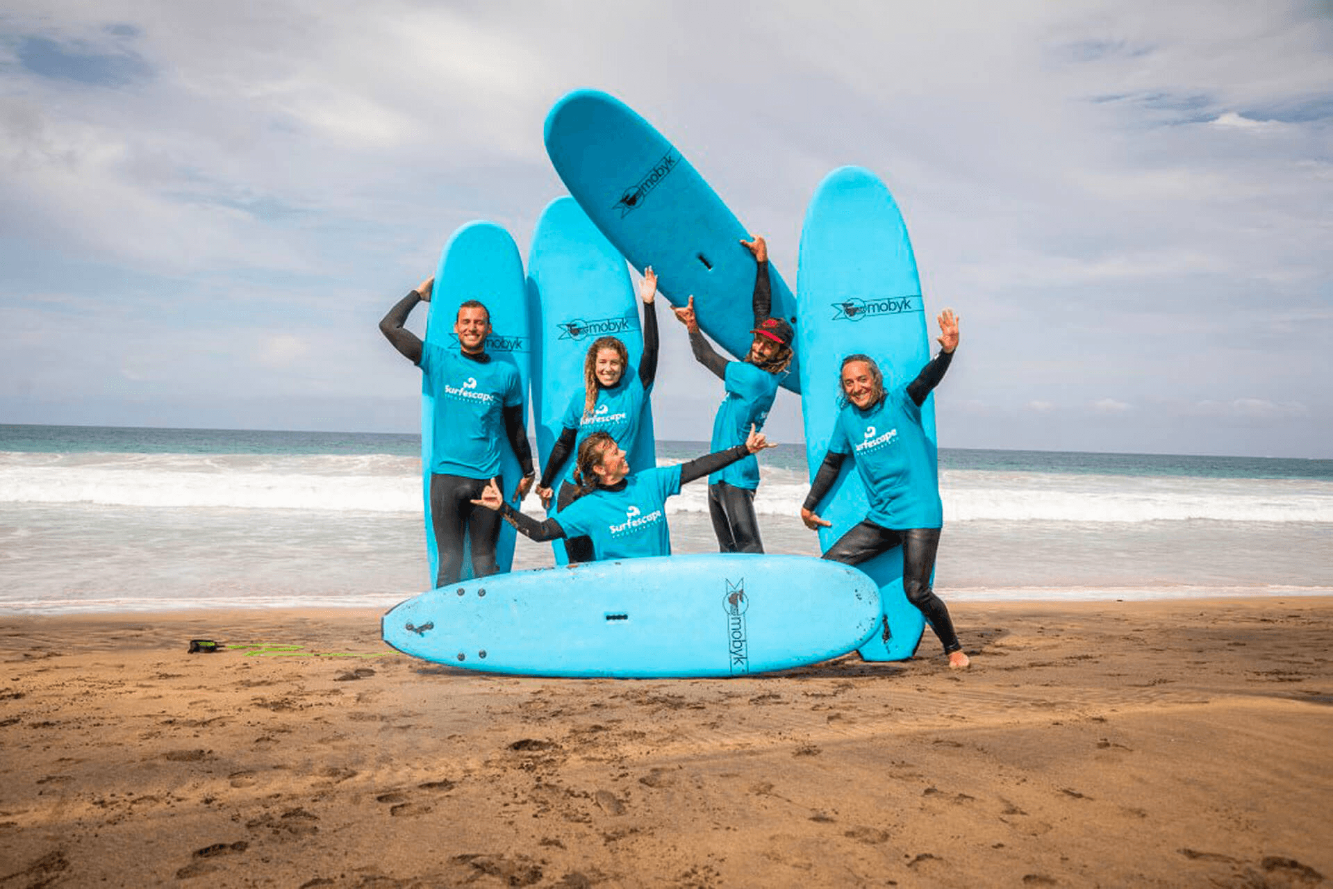 Group of surfers with blue surfboards on the beach