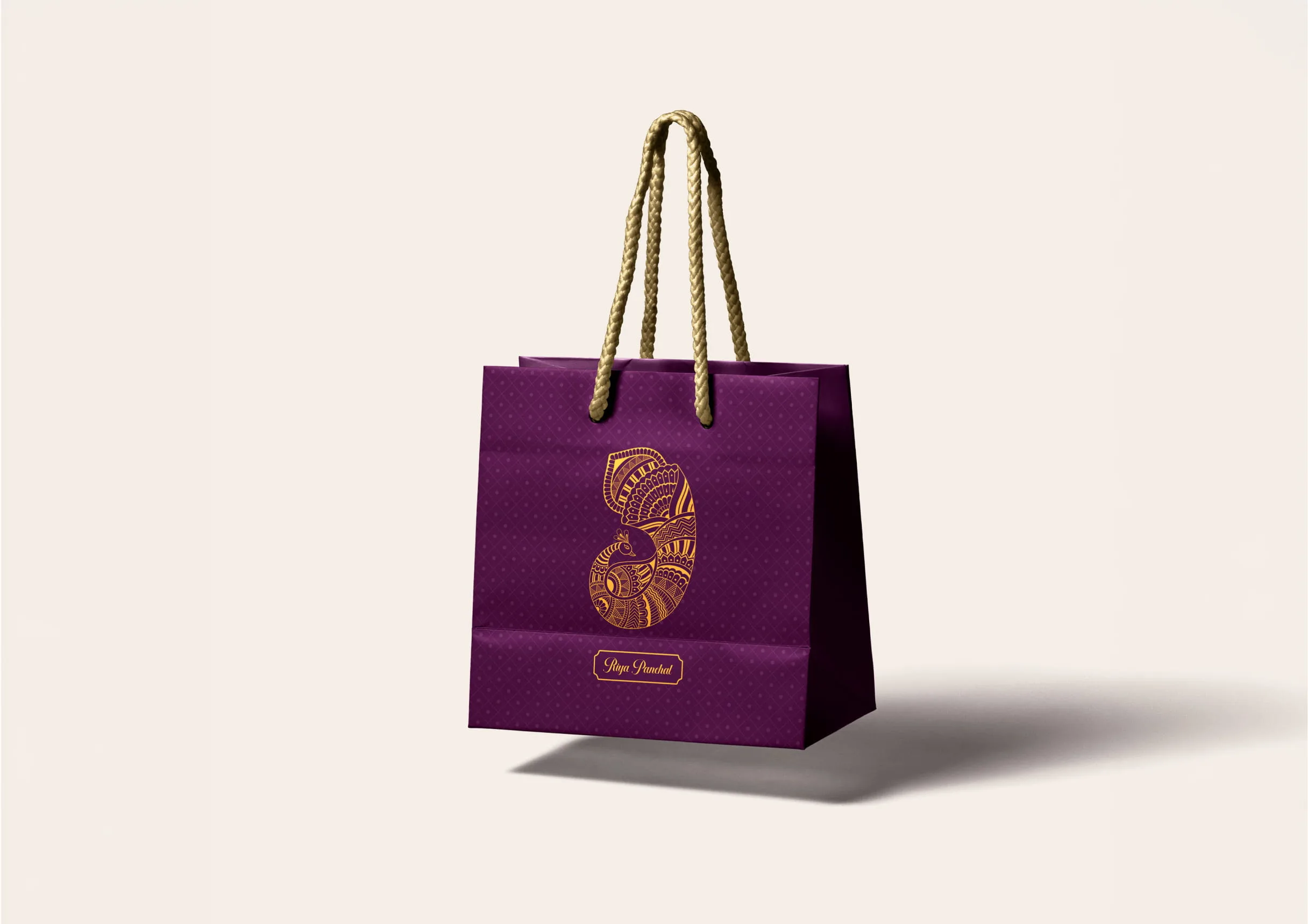 Purple paper shopping bag with twisted rope handles, gold ornamental logo, and a long shadow on a pale studio background; elegant tone.