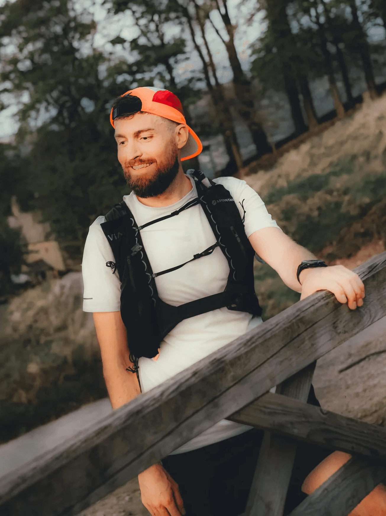 Person wearing a blue puffer jacket and red backpack standing in front of a light blue building on a city street.