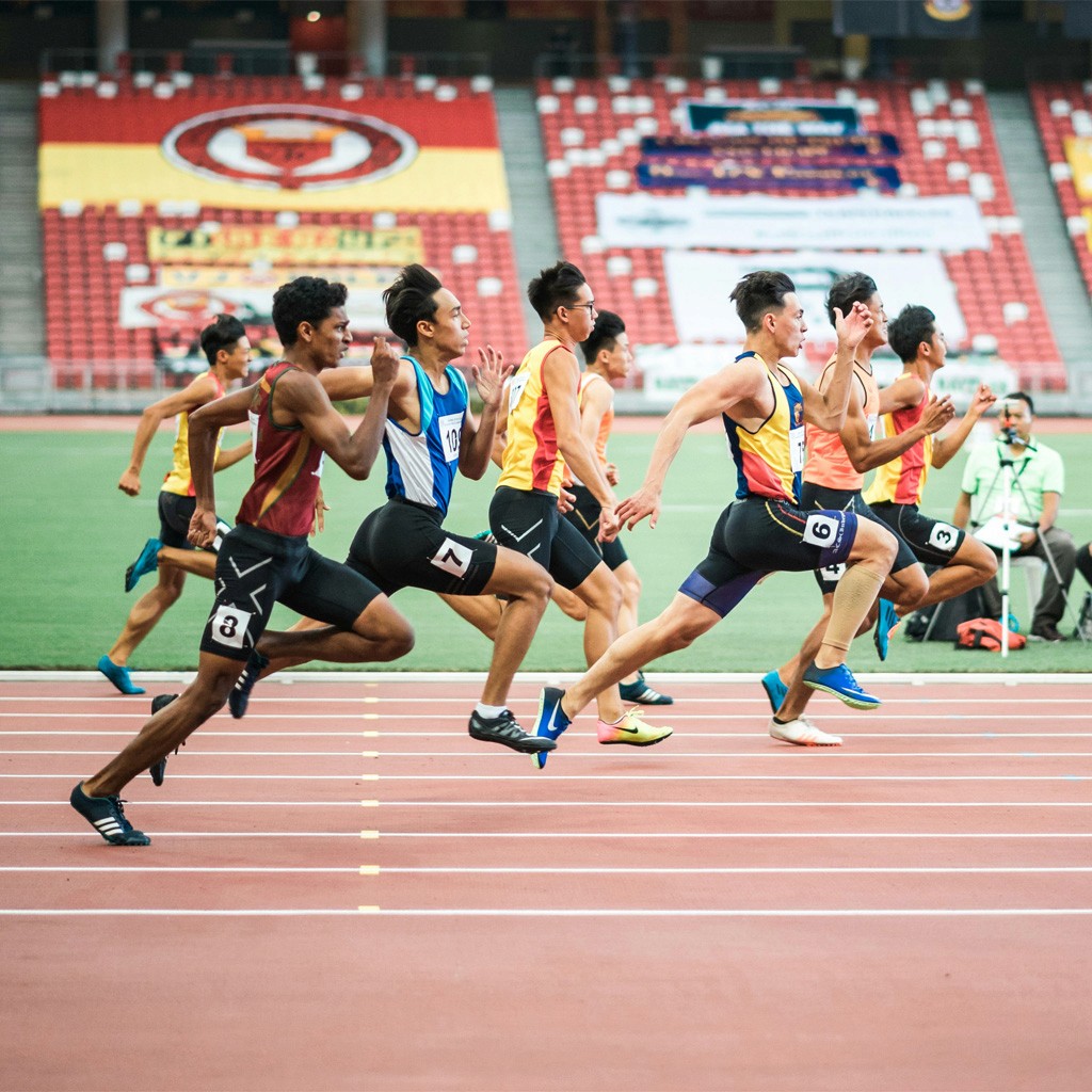  Track and field race with athletes competing in a large outdoor sports venue.