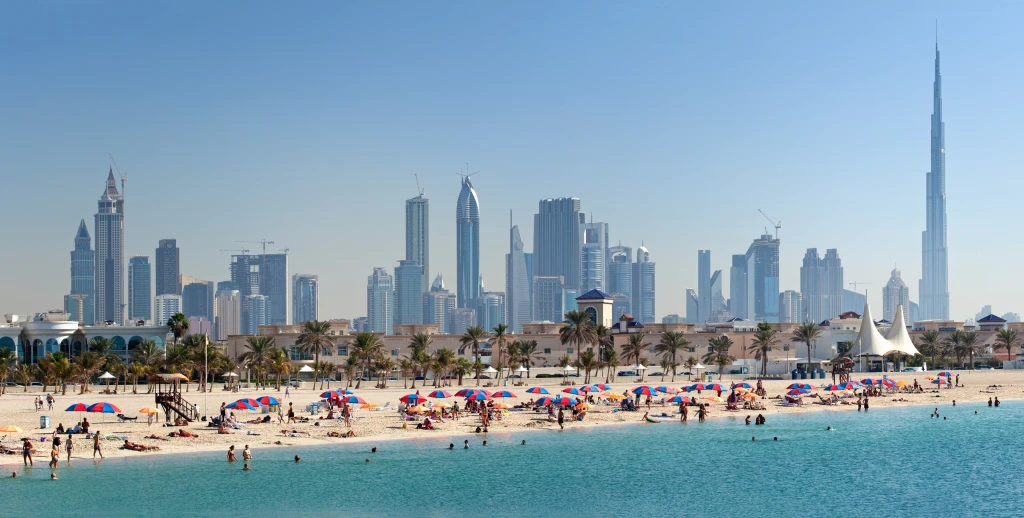 A scenic view of Phoenix beach featuring golden sand, gentle waves, and a clear blue sky with a few scattered clouds.
