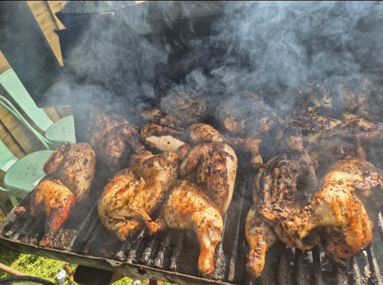 Jerk chicken cooking on a smoky grill at Half Way Tree