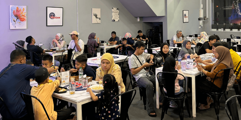 Suasana meriah penuh pelanggan menjamu selera bersama keluarga masing-masing di sebuah kafe di Johor Bahru.