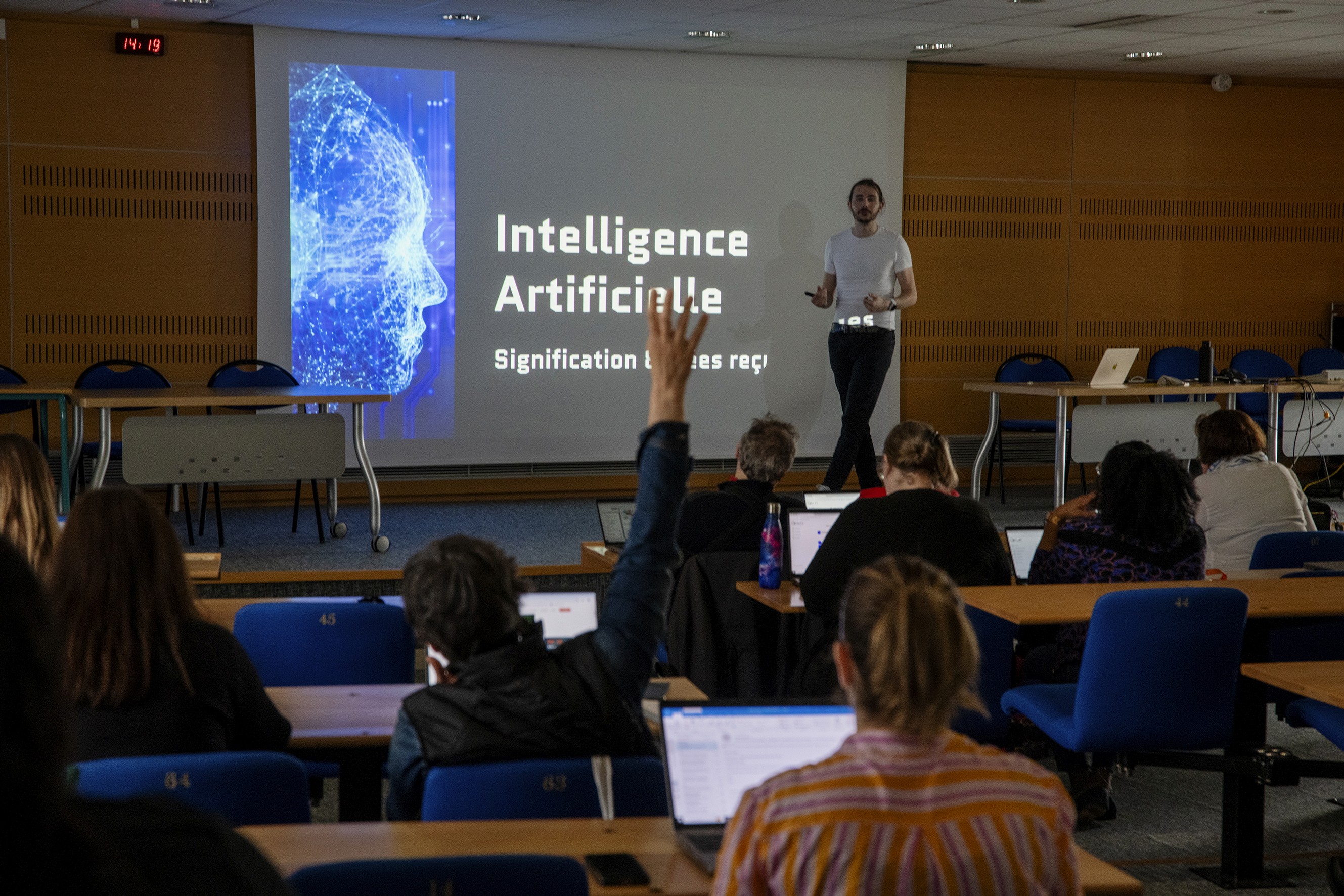 A person holding a camera is silhouetted against vivid orange stage lights. The scene conveys focus and creativity with a dramatic, moody atmosphere.