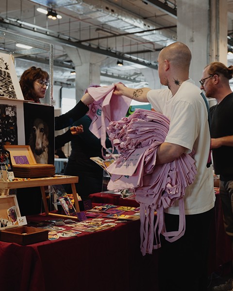 Zdjęcie przedstawiające organizatorów, rozdającyh pamiątkowe torby wystawcom.