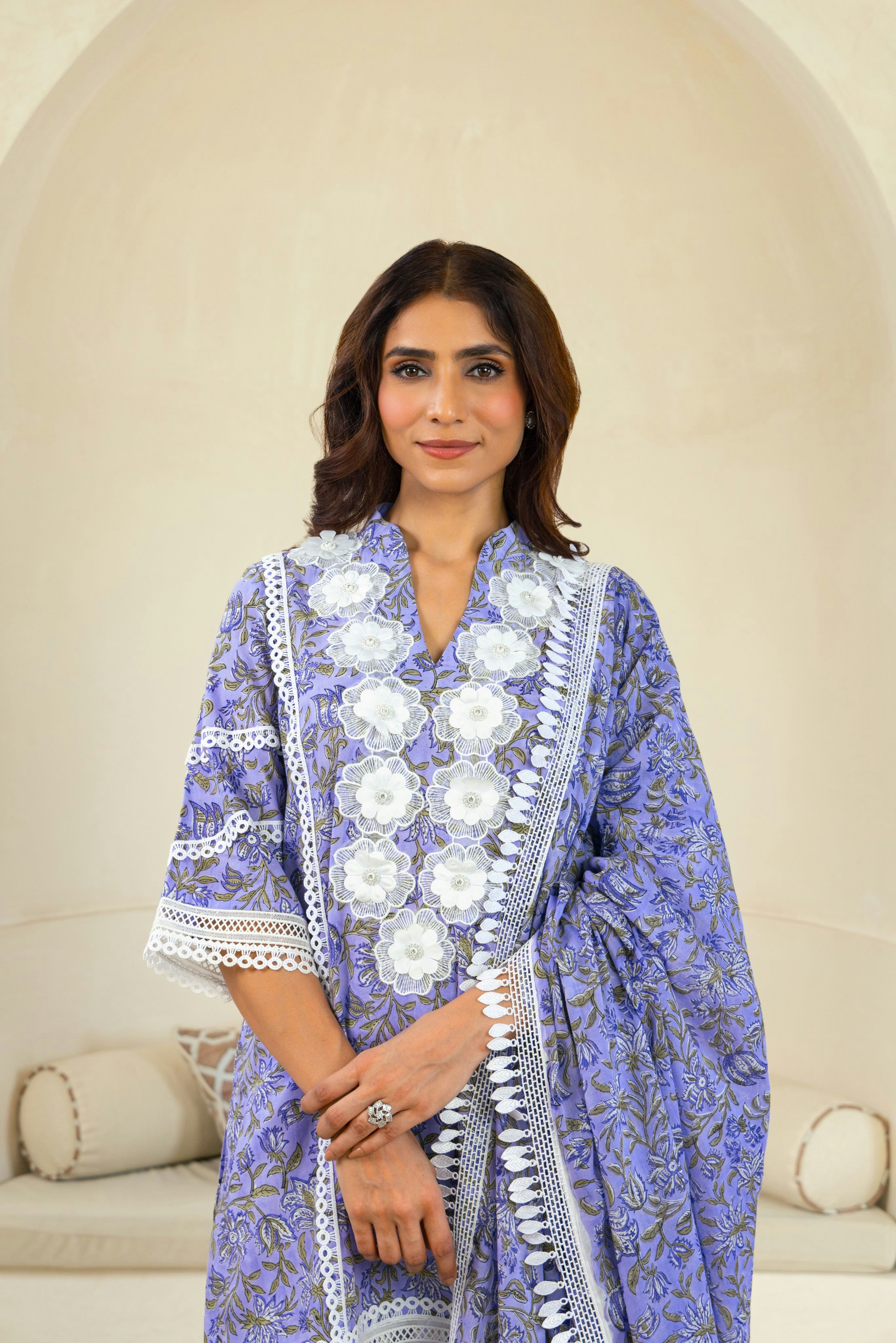 A woman in a blue and white dress standing in front of a couch