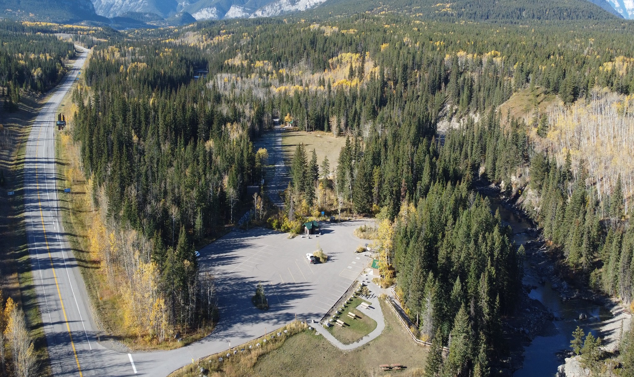 Aerial view of Canoe Meadows parking facility and trails surrounded by forest in autumn in Kananaskis