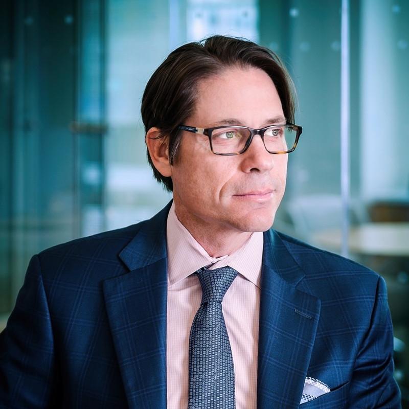 executive in office enviroment dark navy suite pink tshirt and blue tie