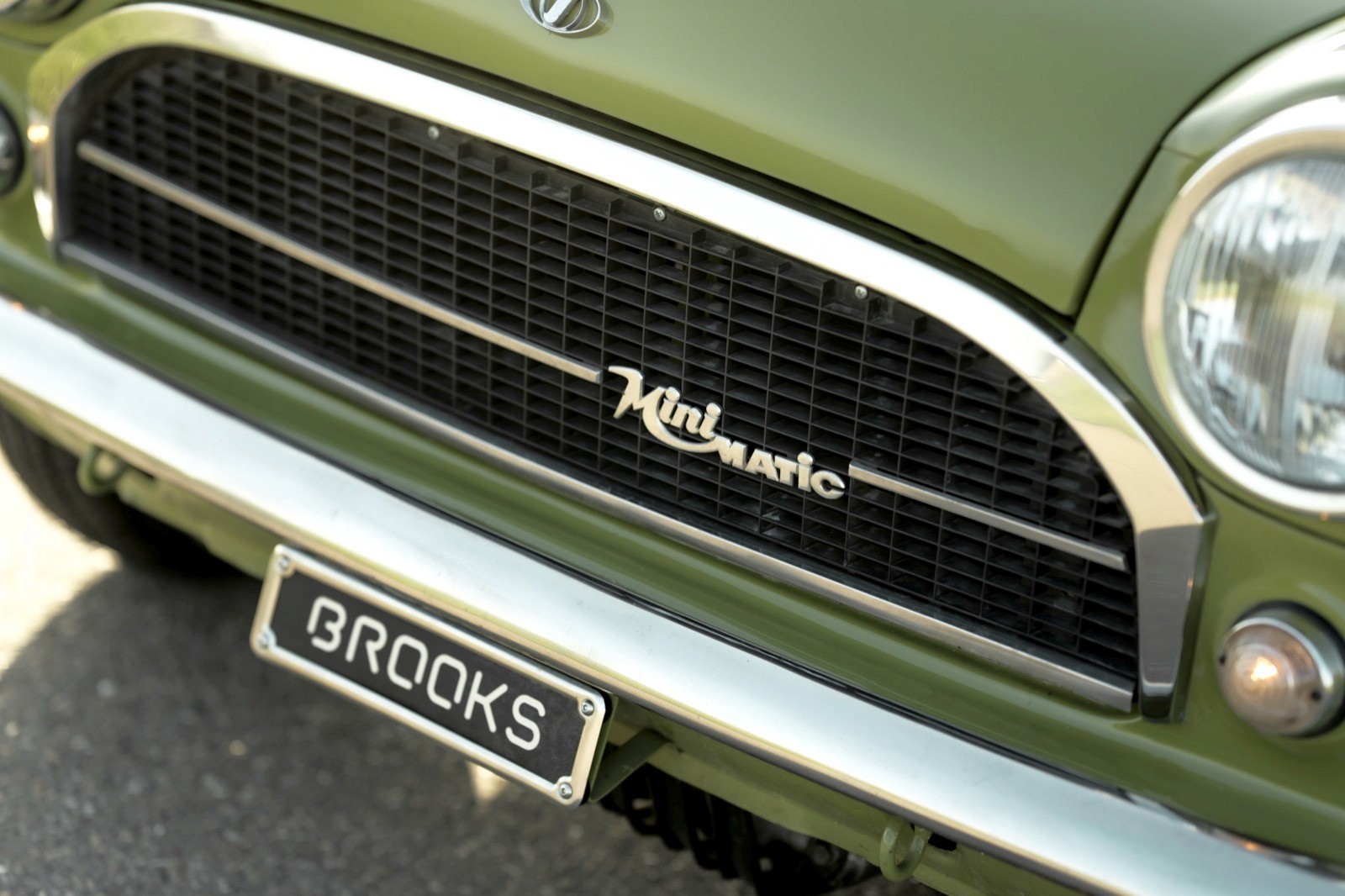 Close-up of a vintage green car's front grille and emblem, showcasing its classic design details.