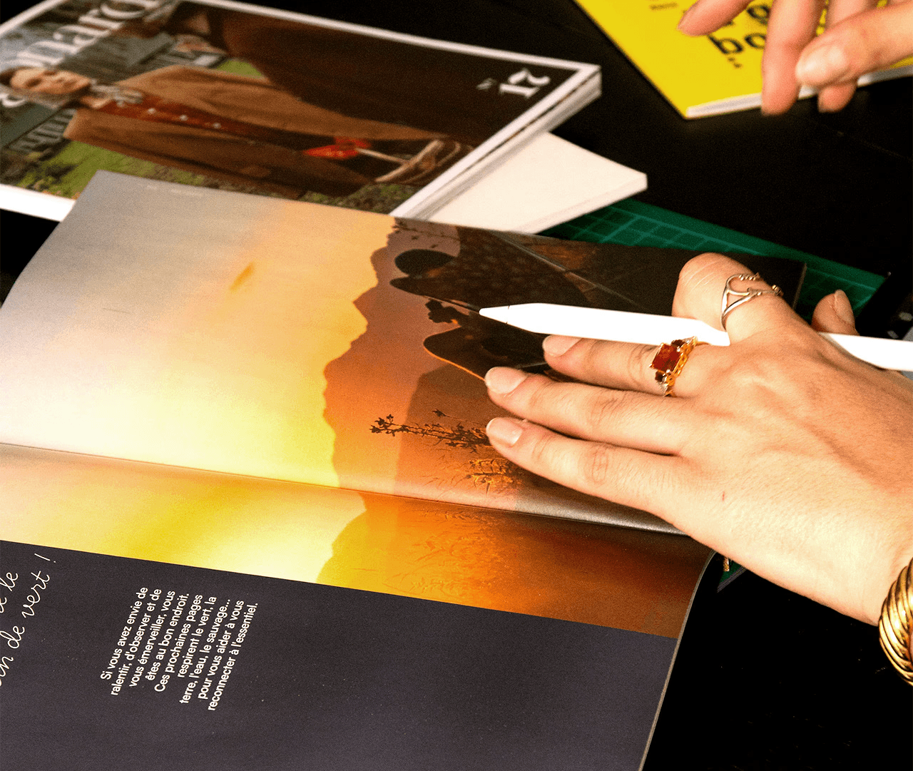 Graphiste annotant avec un stylet une revue photo pour concevoir un moodboard et une direction artistique.