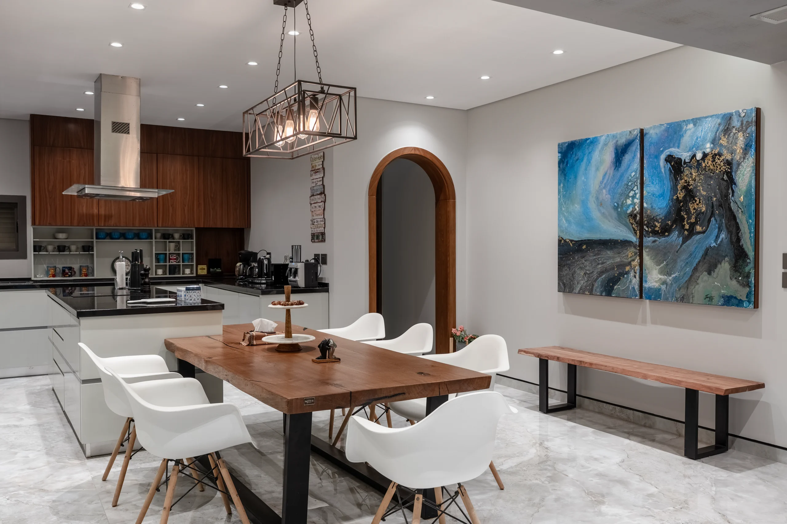 Dining space and fitted kitchen at Caesar SODIC Villa with warm wood finishes and arched doorway.