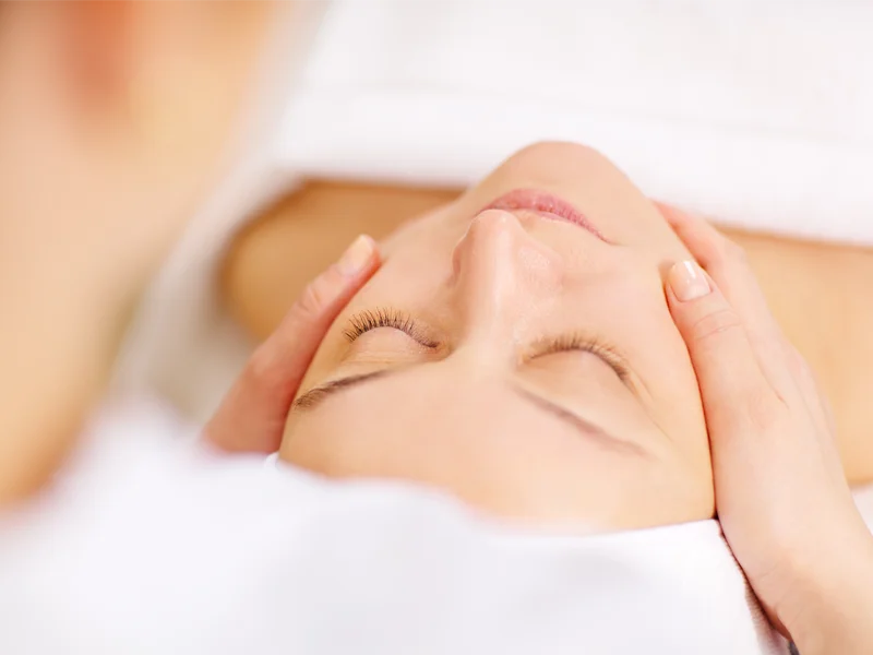 Practitioner performing relaxing facial massage on client's face.