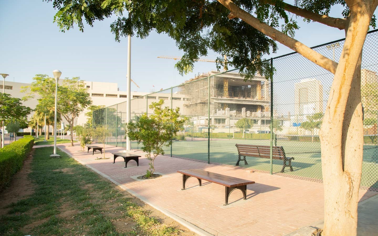 A tennis court featuring benches and trees in the background, located in District 1.