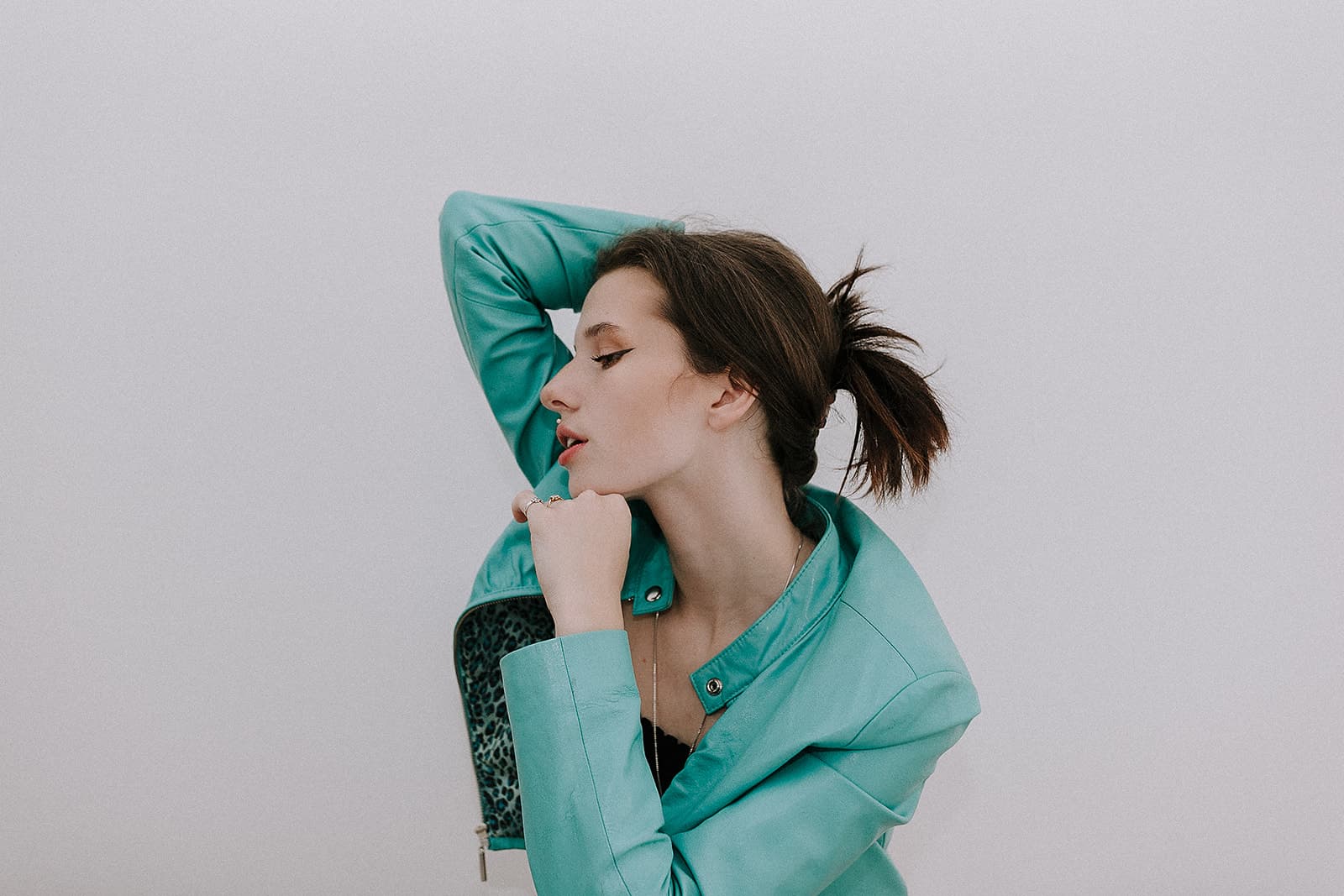 Model with a teal jacket poses with one arm behind her head at Revelator Studio in Shreveport for a 90s-inspired fashion shoot.