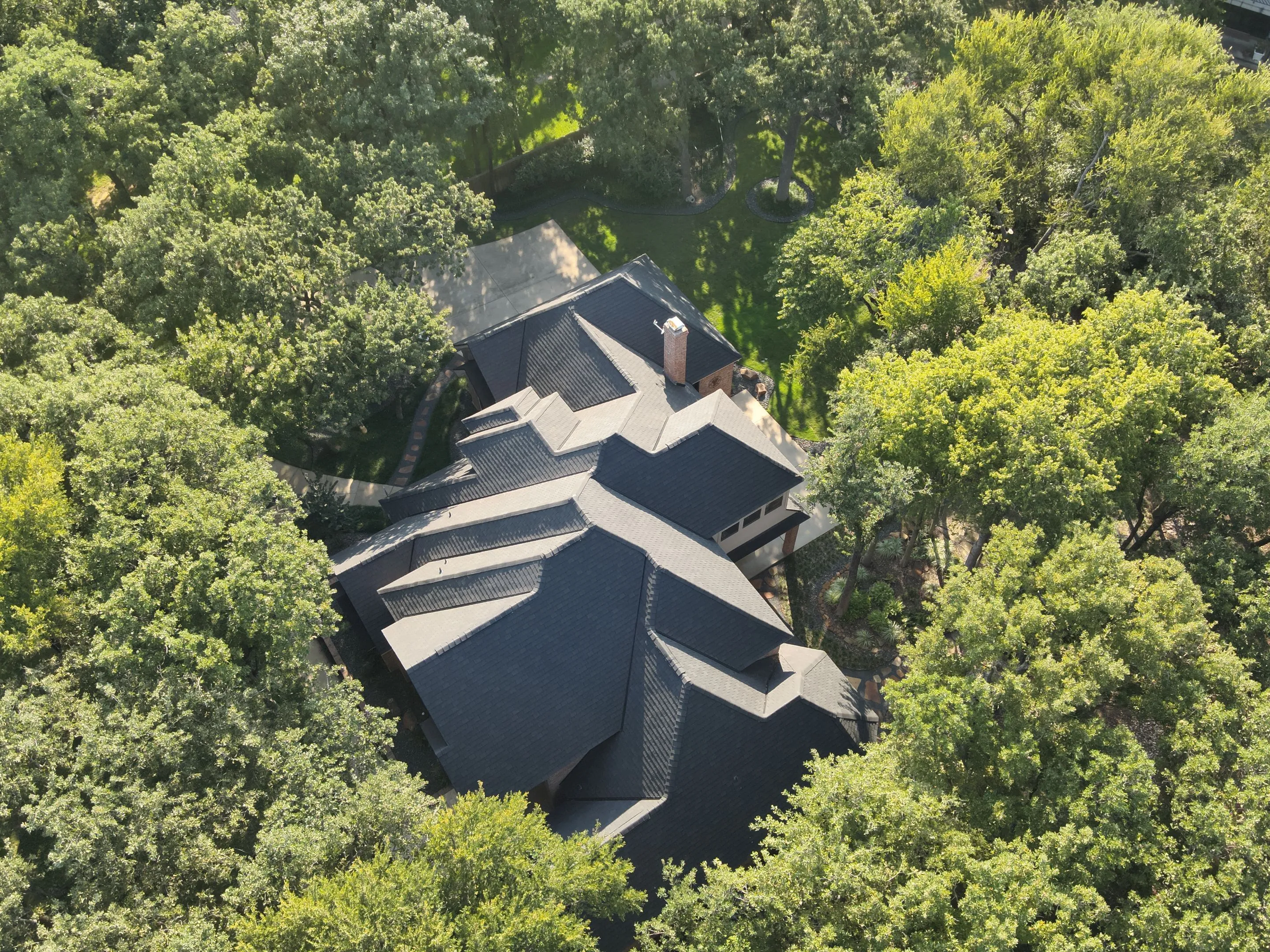 Aerial view of completed F-Wave synthetic roof installation on large Corinth Texas home showing complex multi-level architecture and premium roofing materials